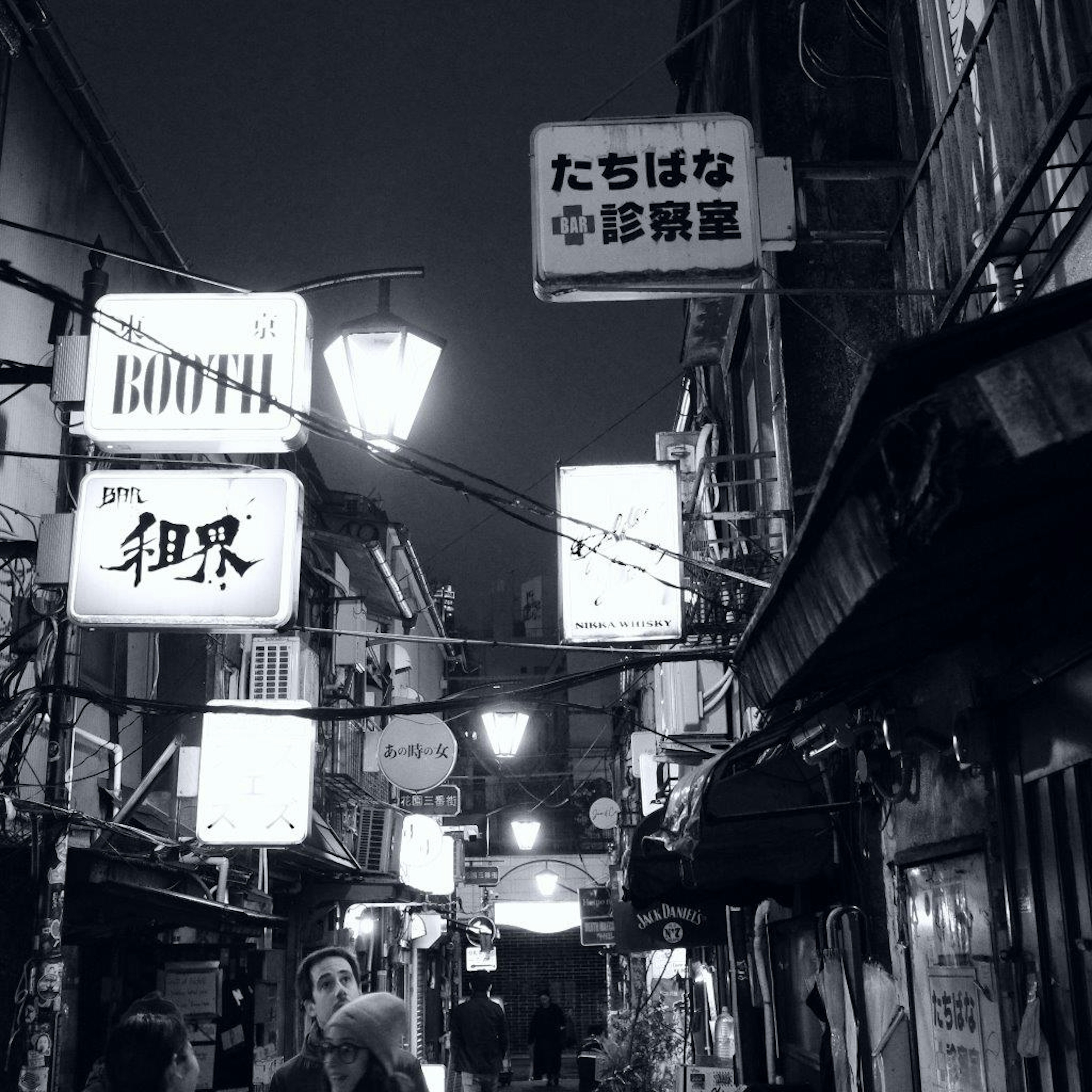 Nighttime street scene featuring restaurant signs and people