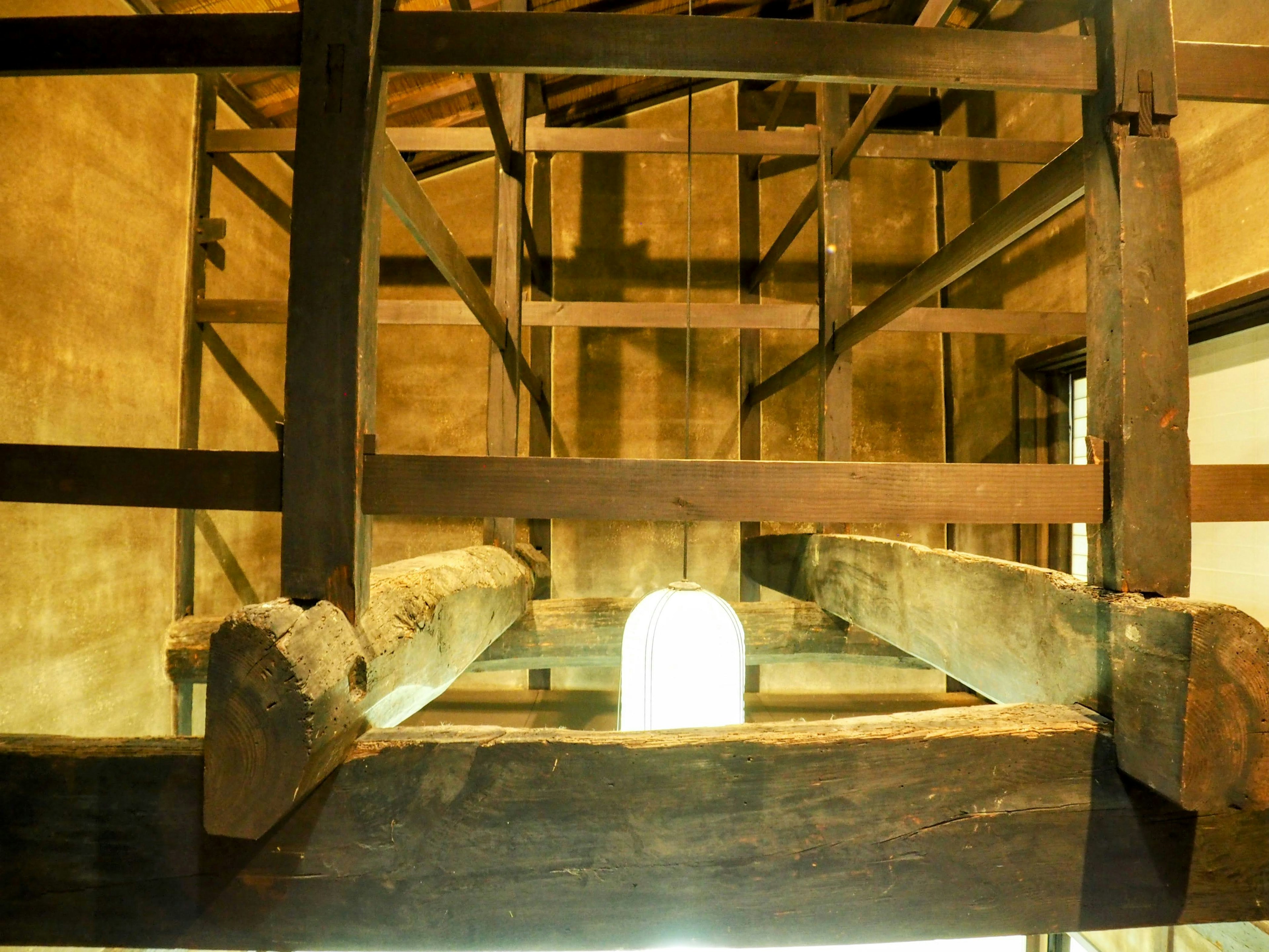 Vista interior de una antigua estructura de madera mostrando vigas y luz