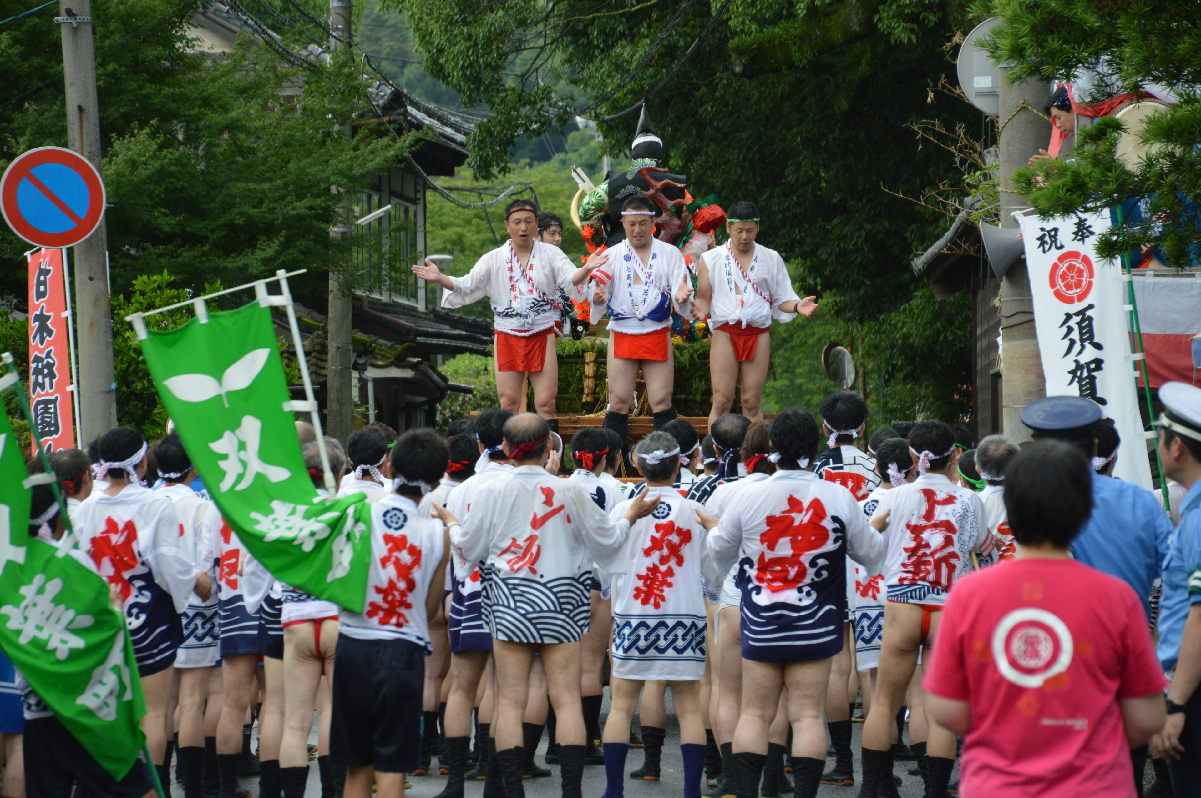 Traditional festival parade with participants in red and white attire carrying a portable shrine