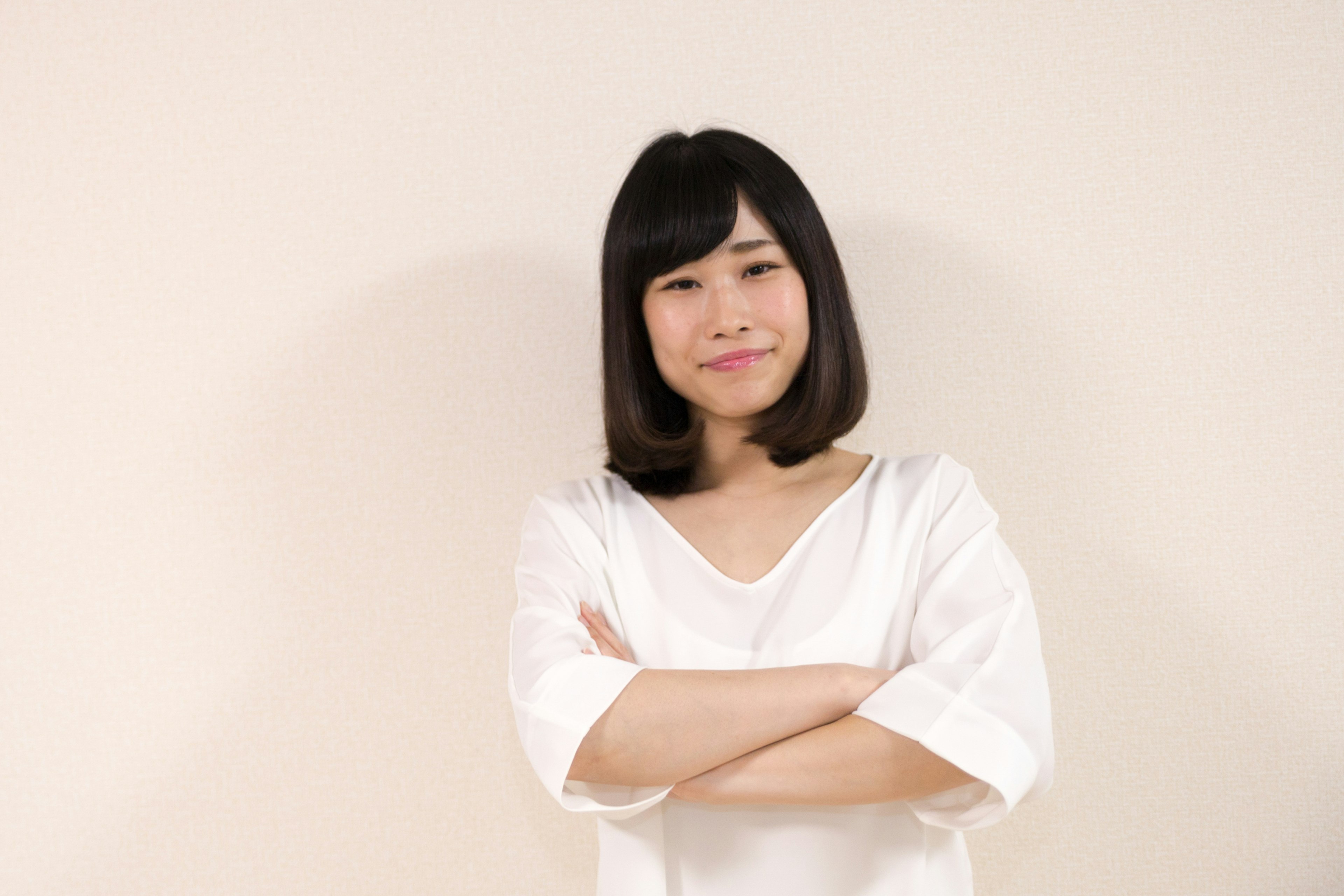 Une femme en chemise blanche avec les bras croisés souriant