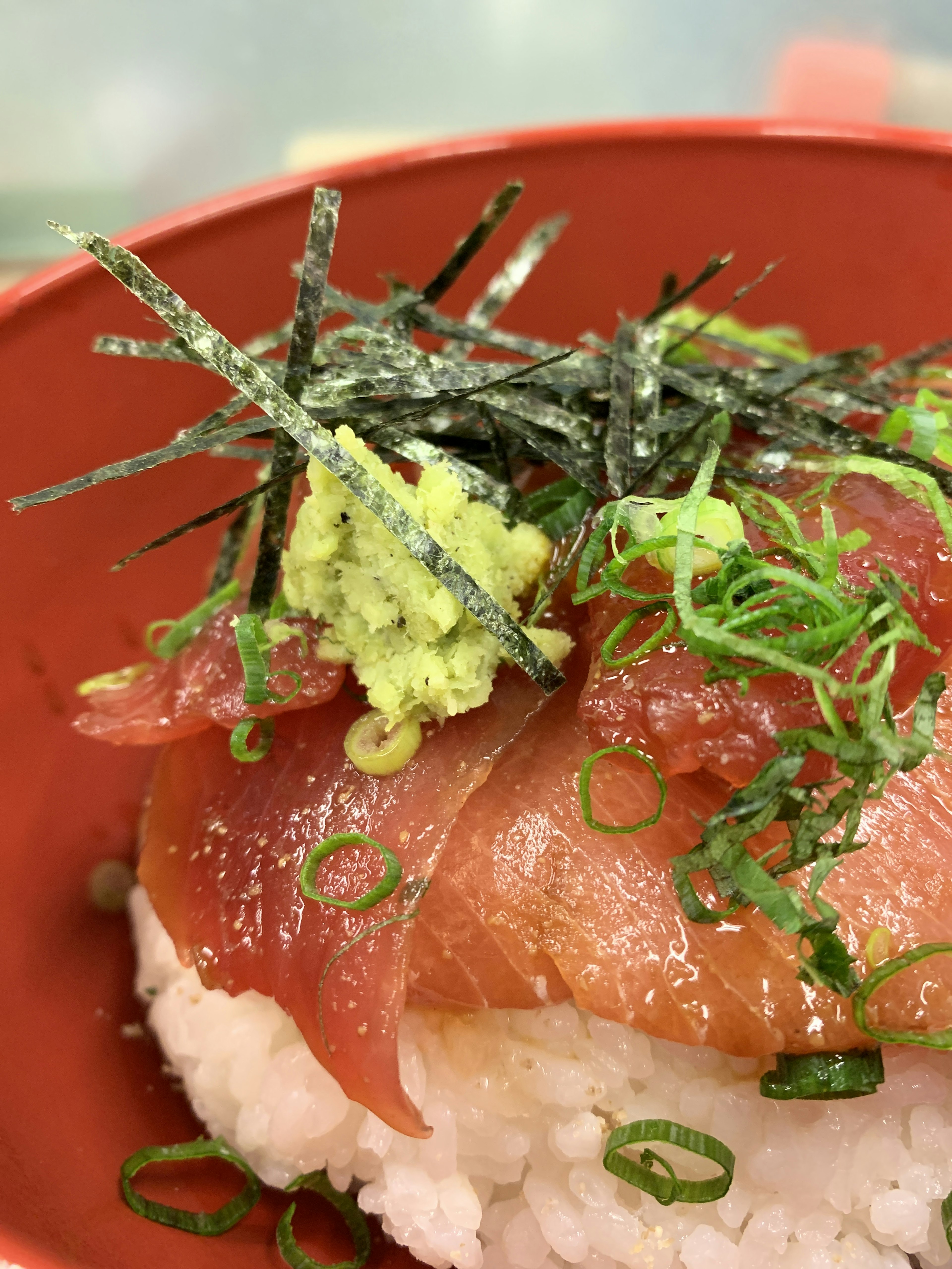 Fette di sashimi su riso guarnito con wasabi e cipolle verdi con alga