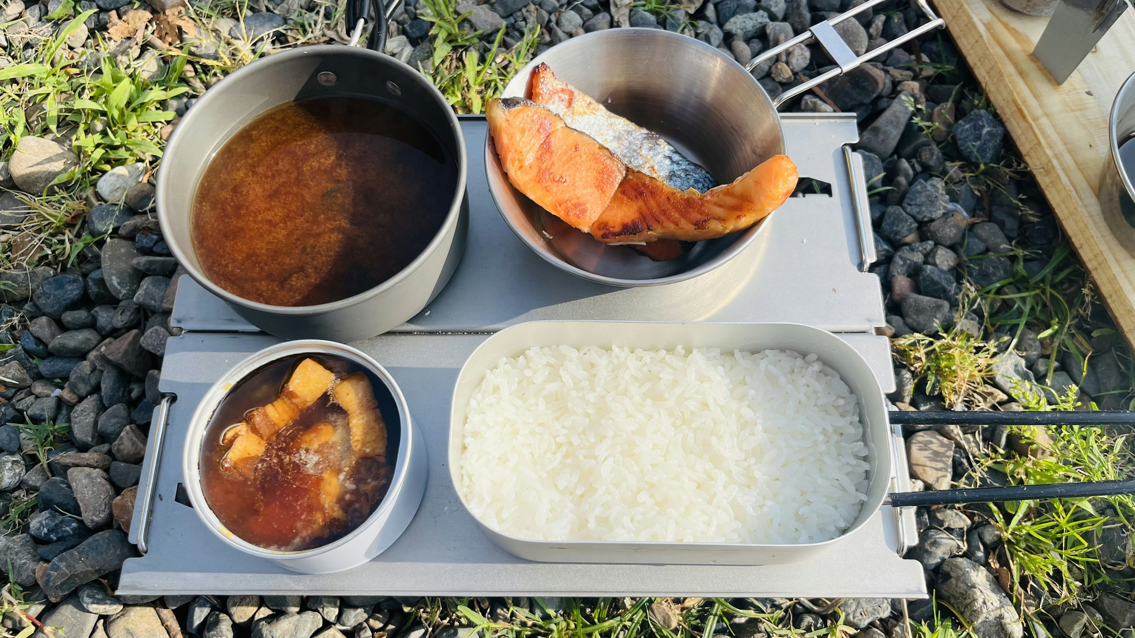 アウトドア料理のセットに盛り付けられた白ご飯と魚の煮物