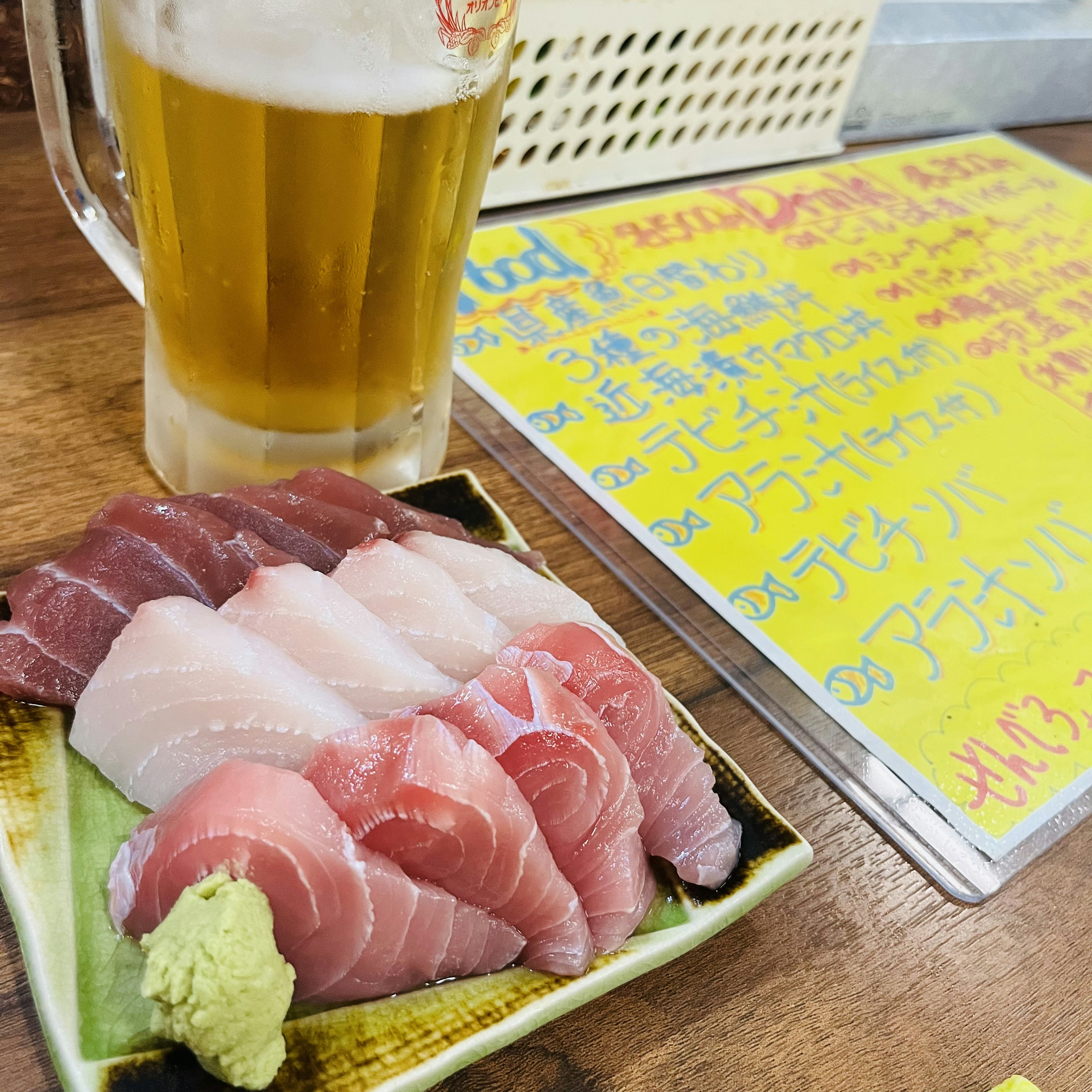 Une assiette de sashimi assorti avec une bière sur la table menu coloré en arrière-plan