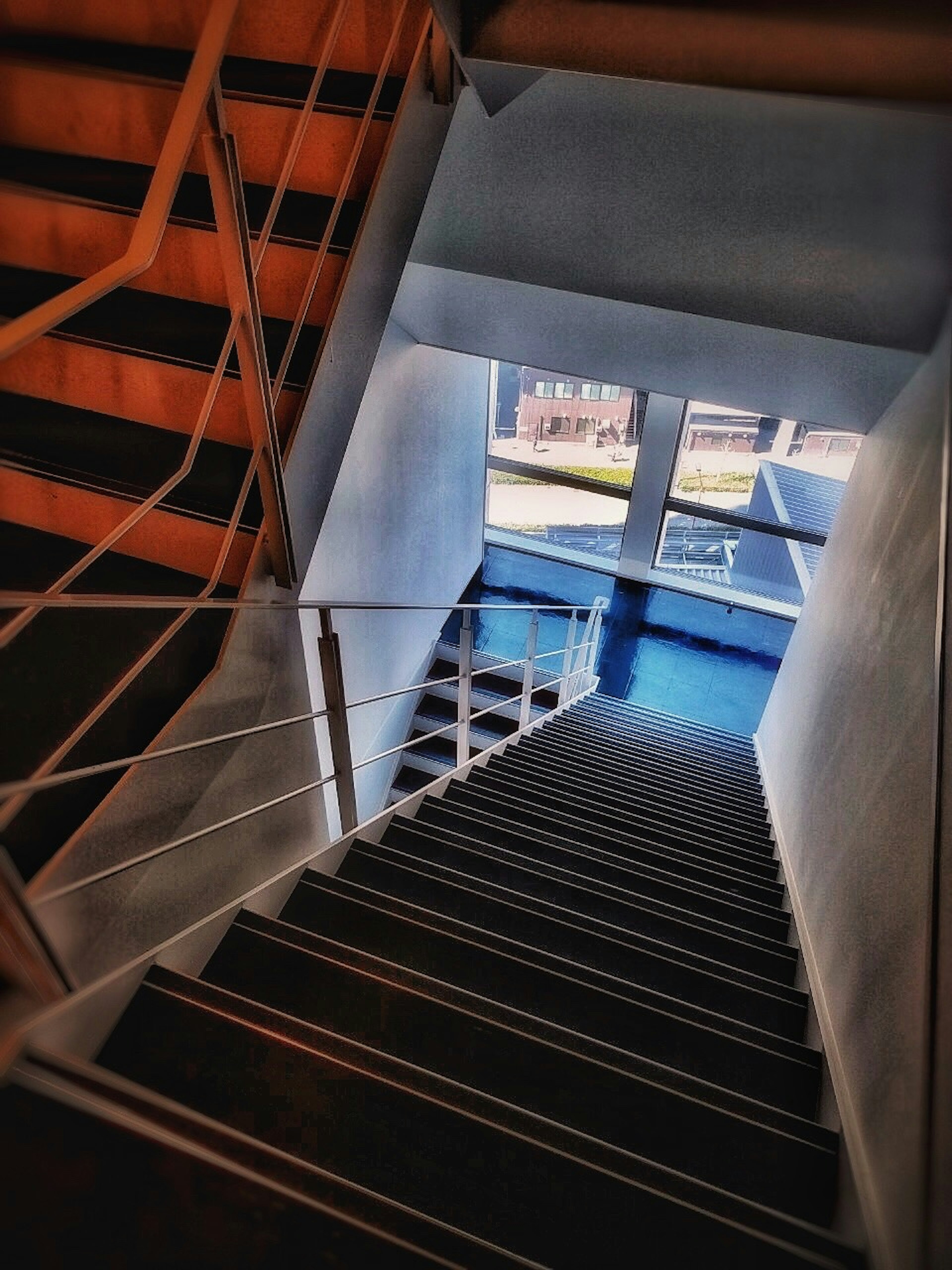 View from the bottom of a staircase with light streaming through a window revealing a blue surface