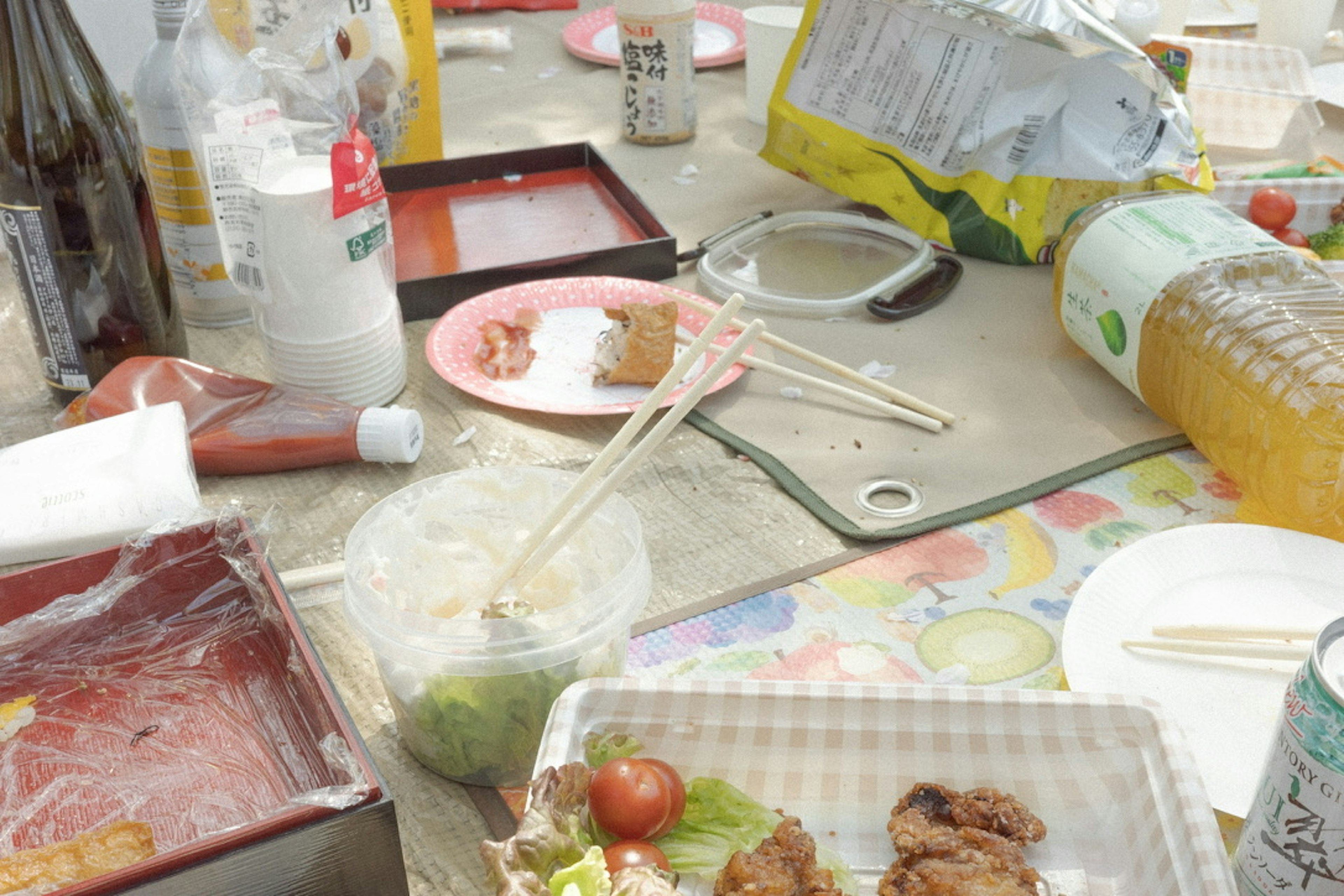 Una mesa de picnic desordenada con comida y bebidas sobrantes