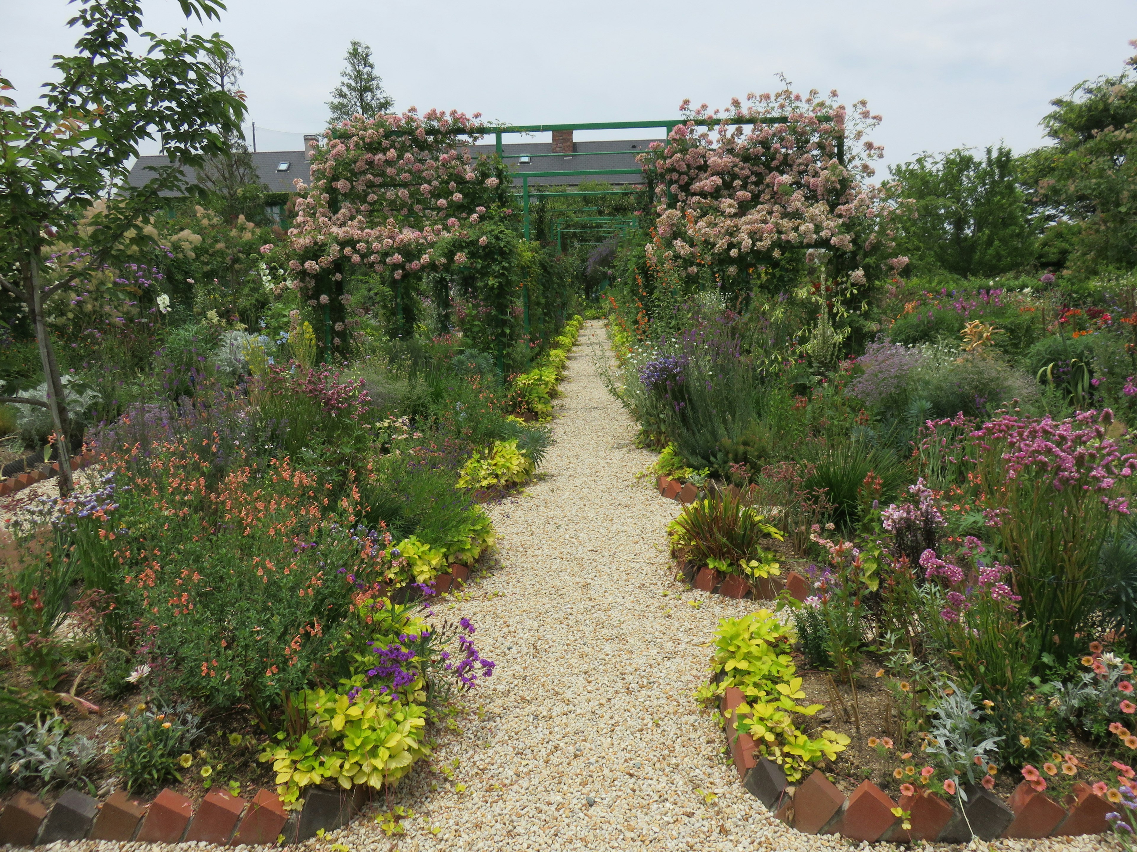 Ein schöner Gartenweg gesäumt von bunten Blumen und Grün