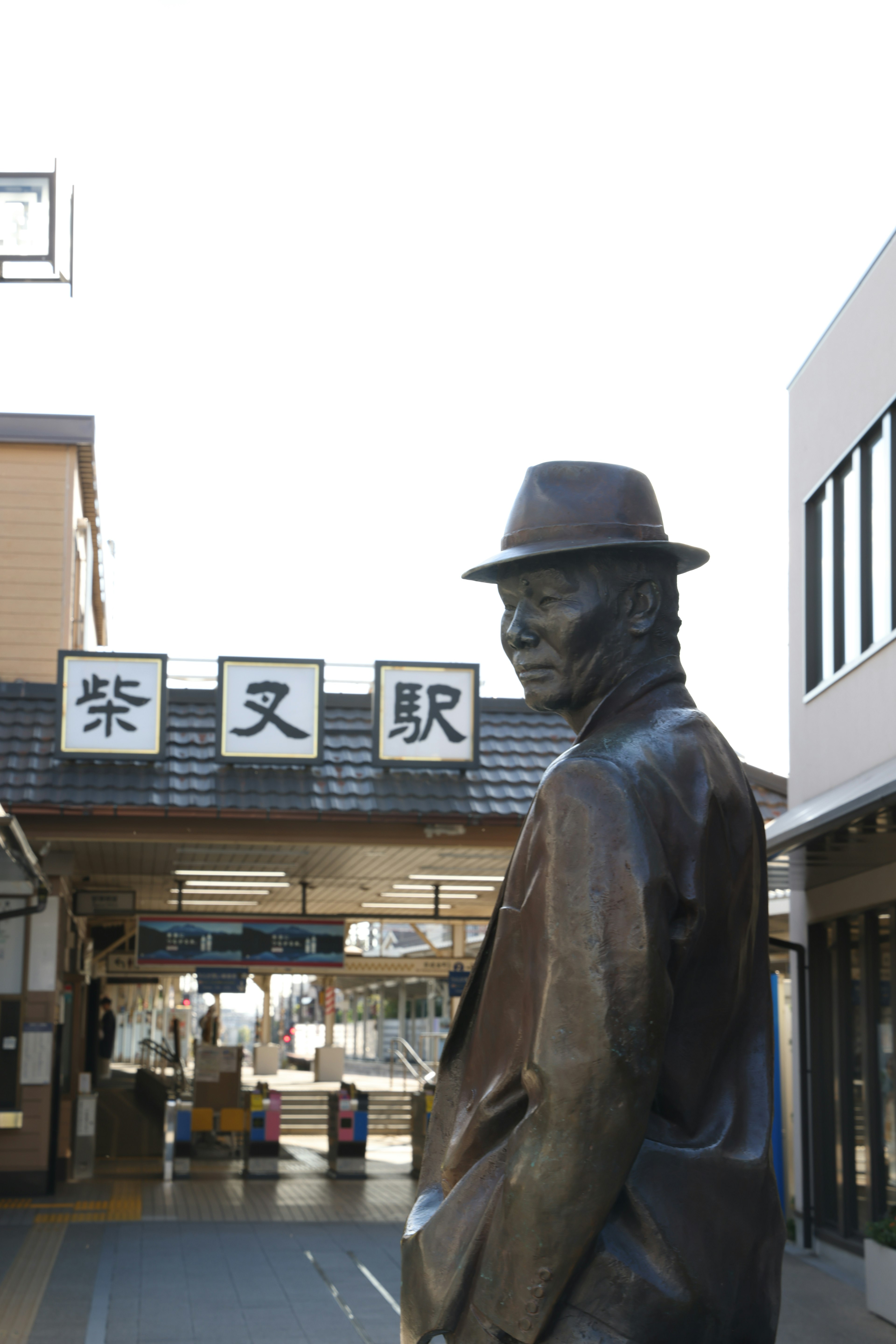 Bronze statue in front of a train station with signage