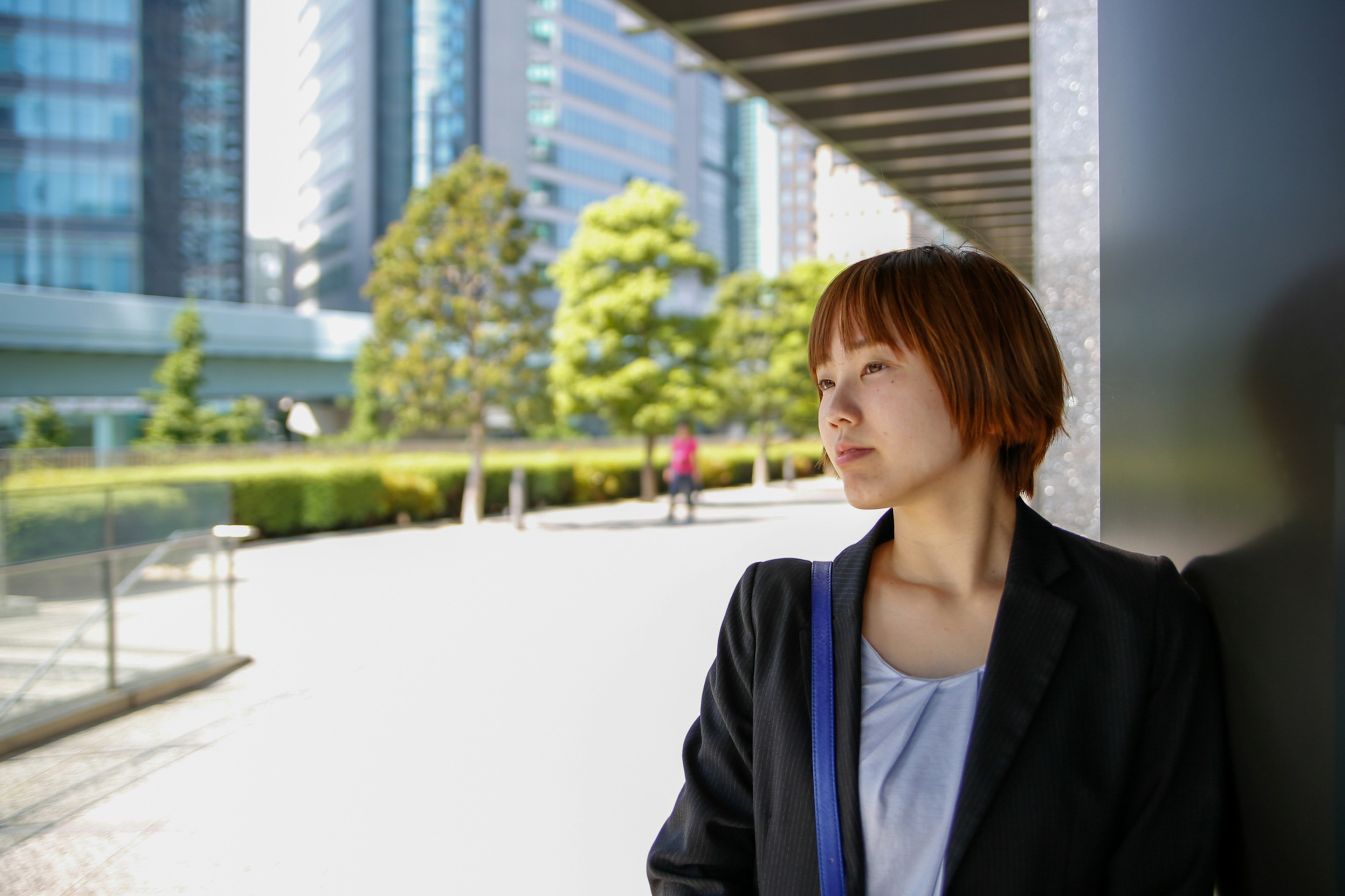 A woman in business attire lost in thought against an urban backdrop