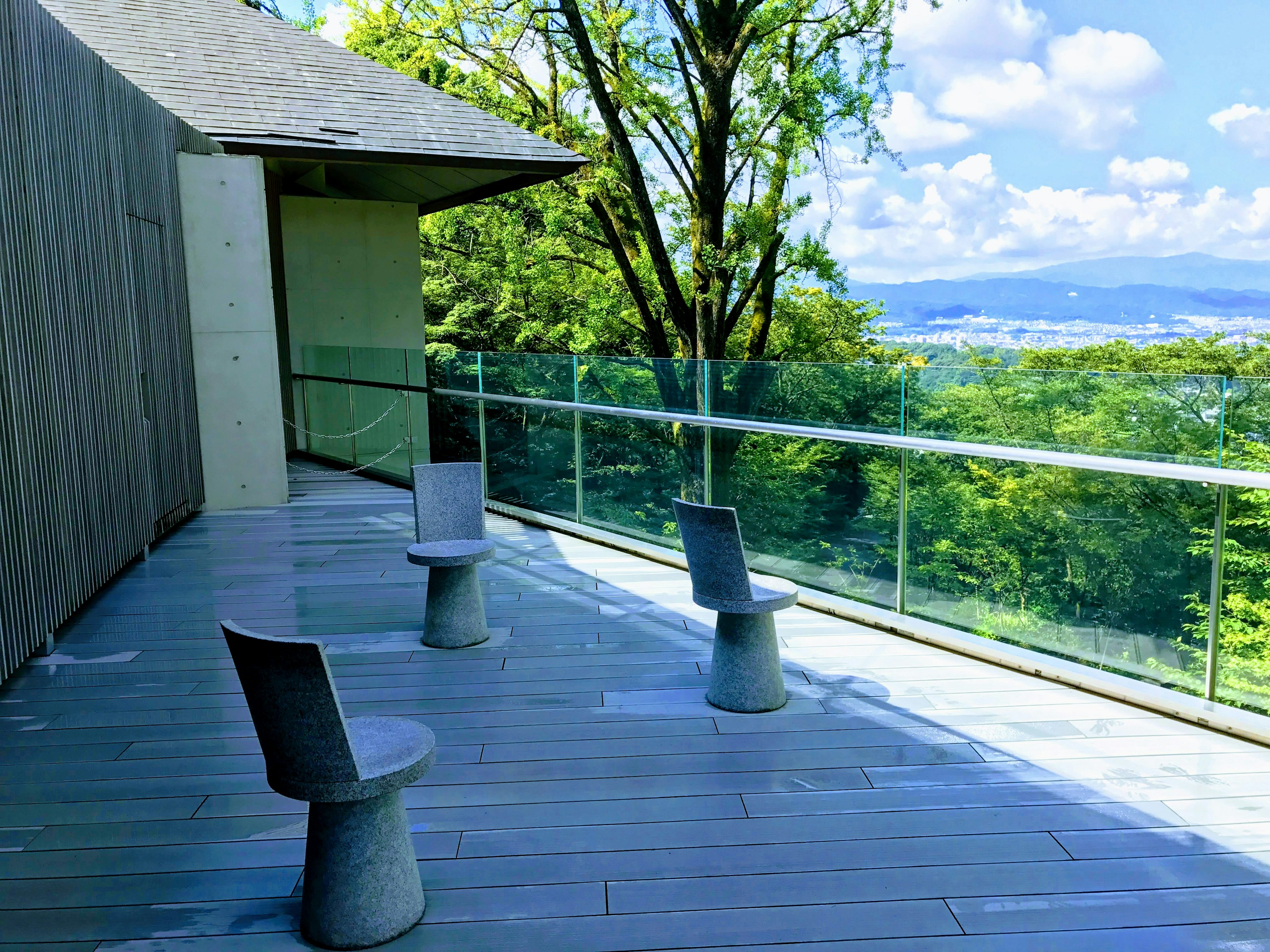 Terrasse mit drei zylindrischen Stühlen mit Blick auf üppiges Grün