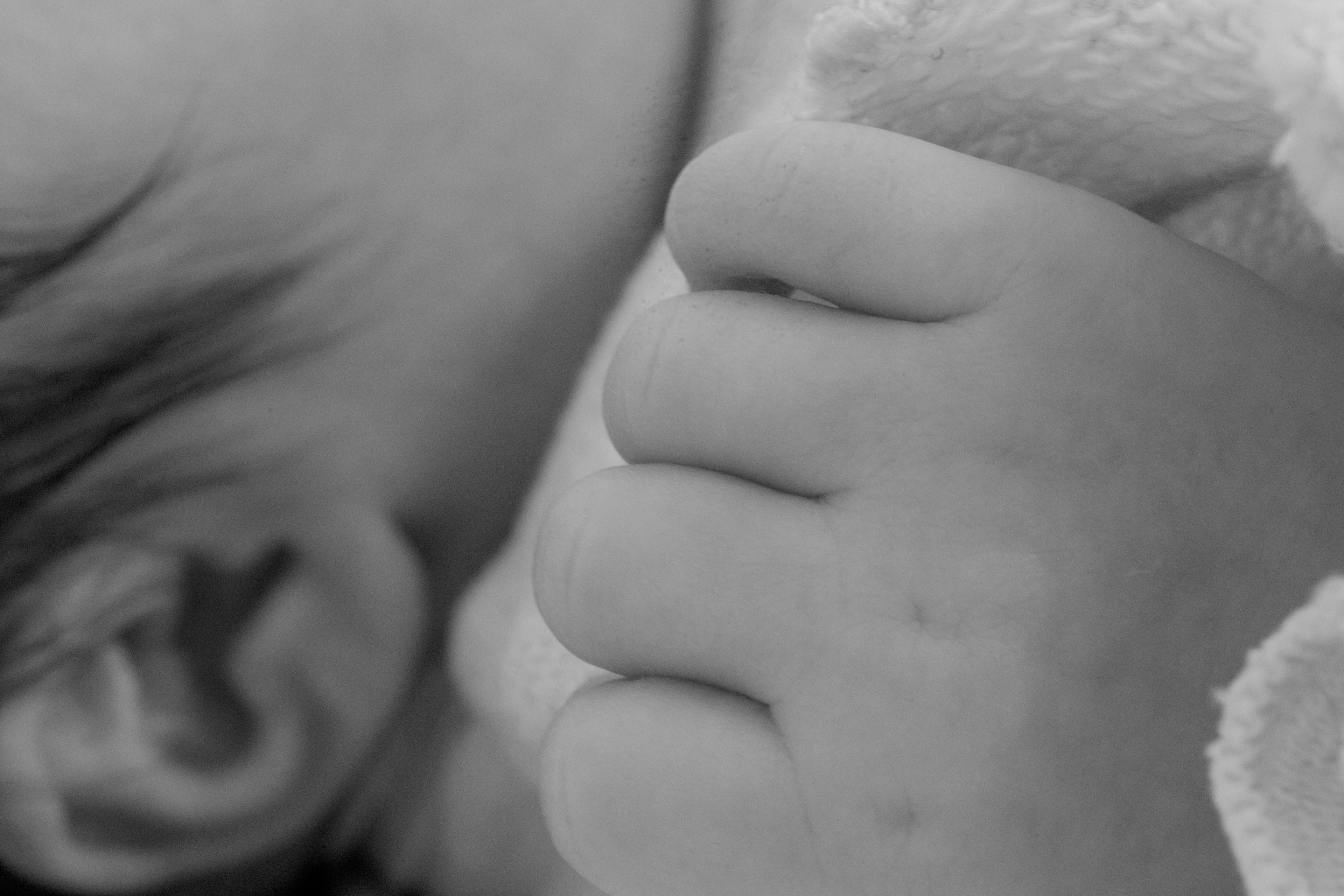 Close-up of a baby's hand and ear in black and white