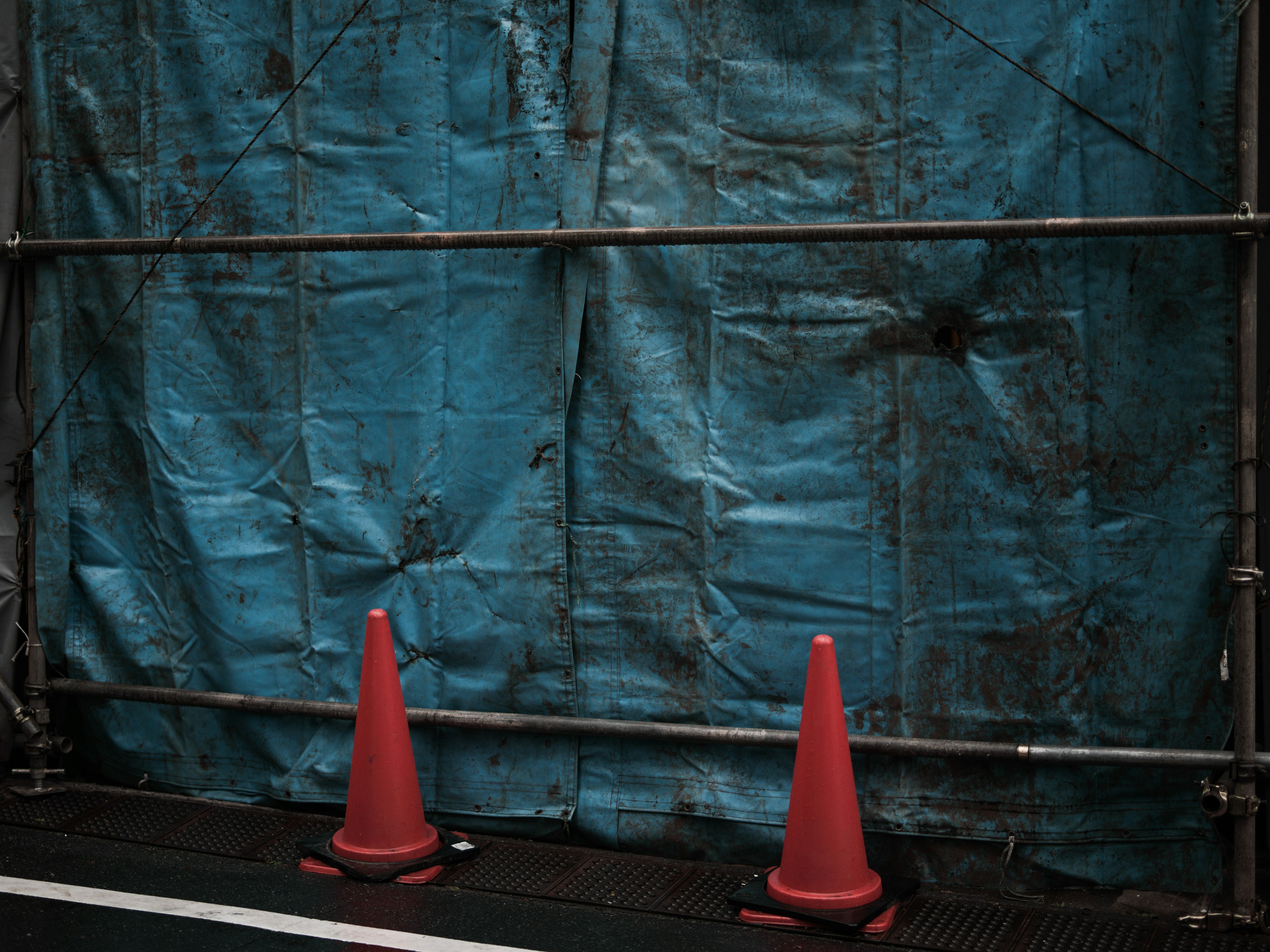 Image of a construction site featuring a blue tarp and two red cones