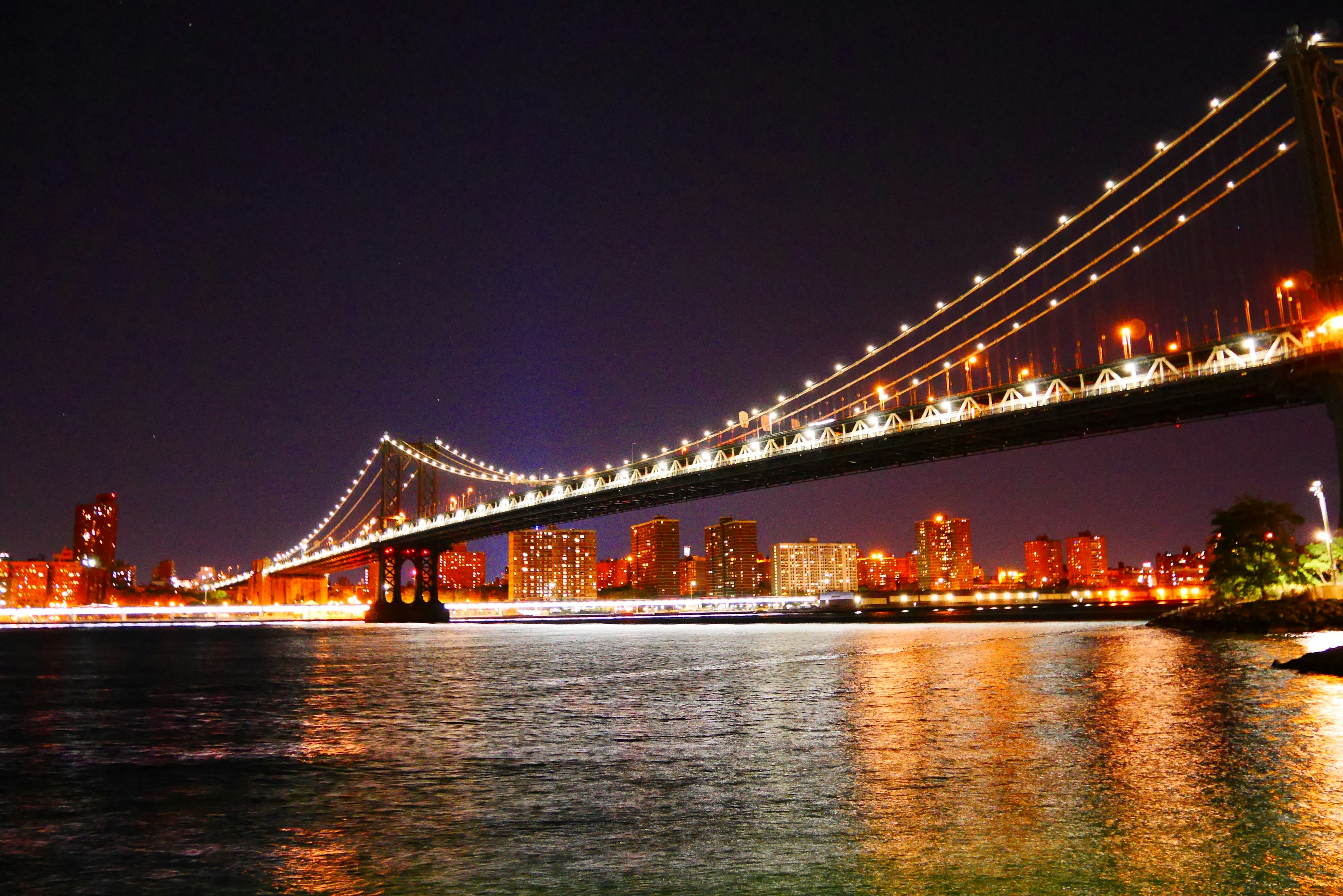 Hermosa vista del puente de Manhattan de noche con luces de la ciudad brillantes