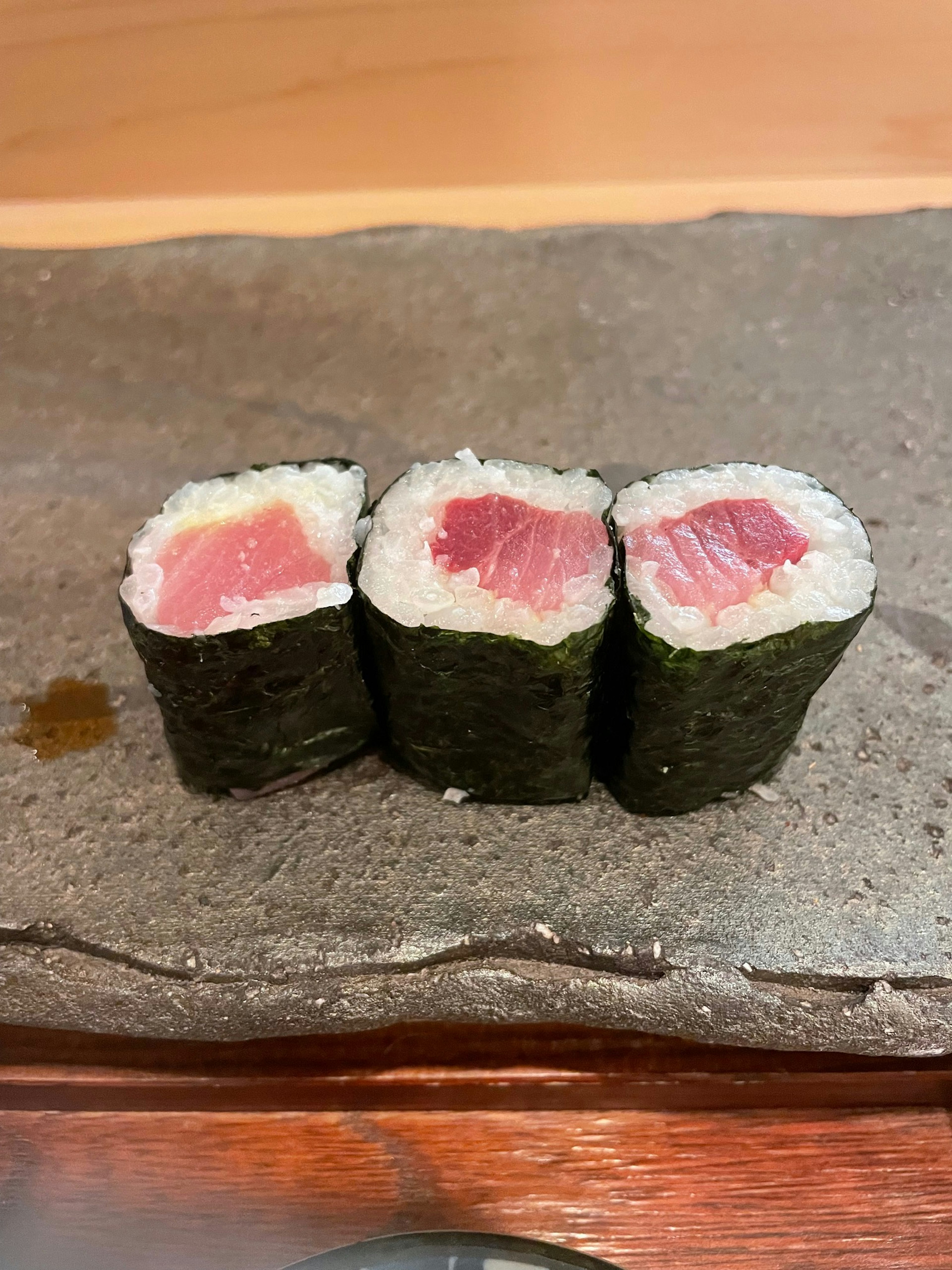 Three sushi rolls showcasing fresh tuna in cross-section