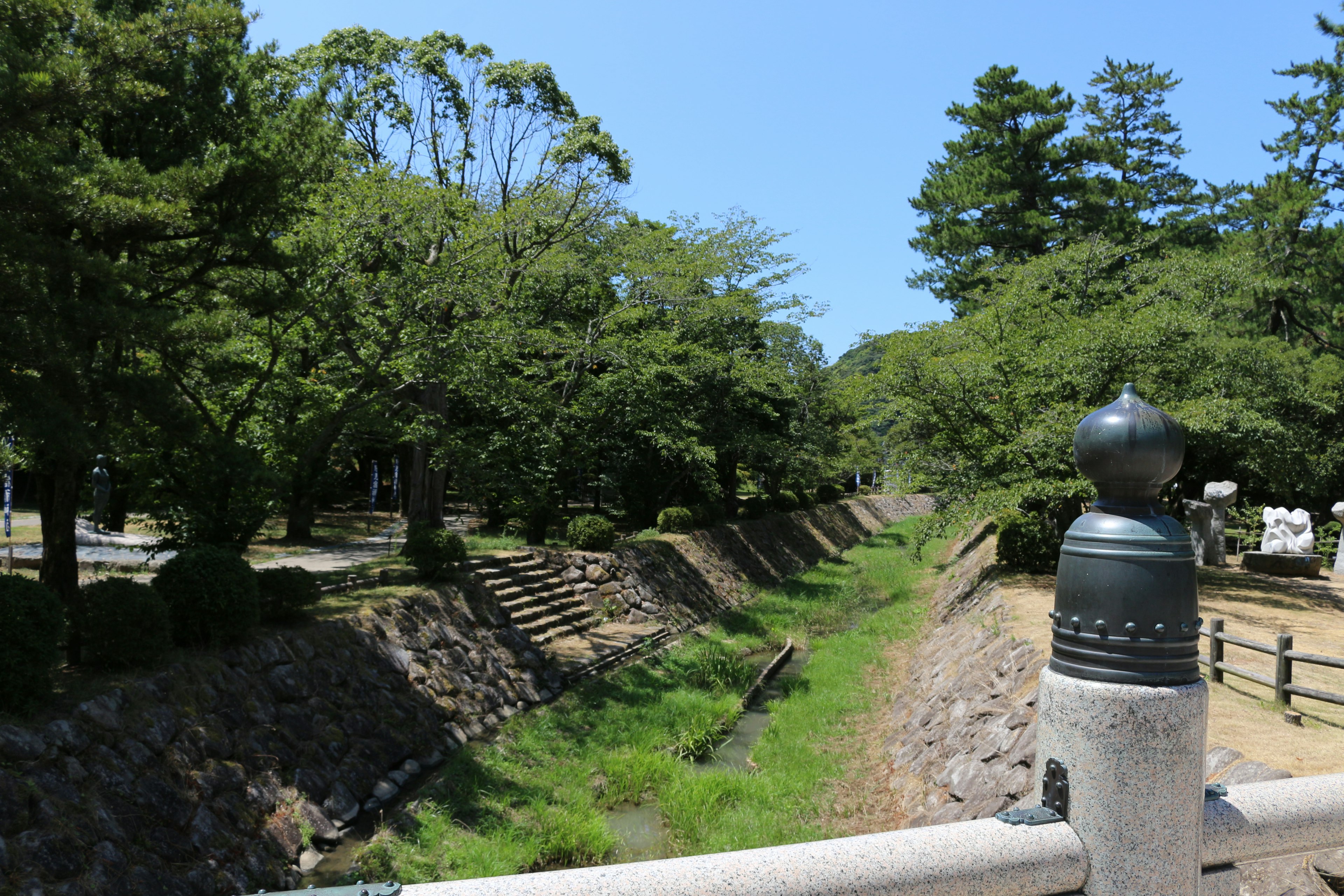 Vista panoramica di un parco verdeggiante e di un fiume sotto un cielo blu chiaro