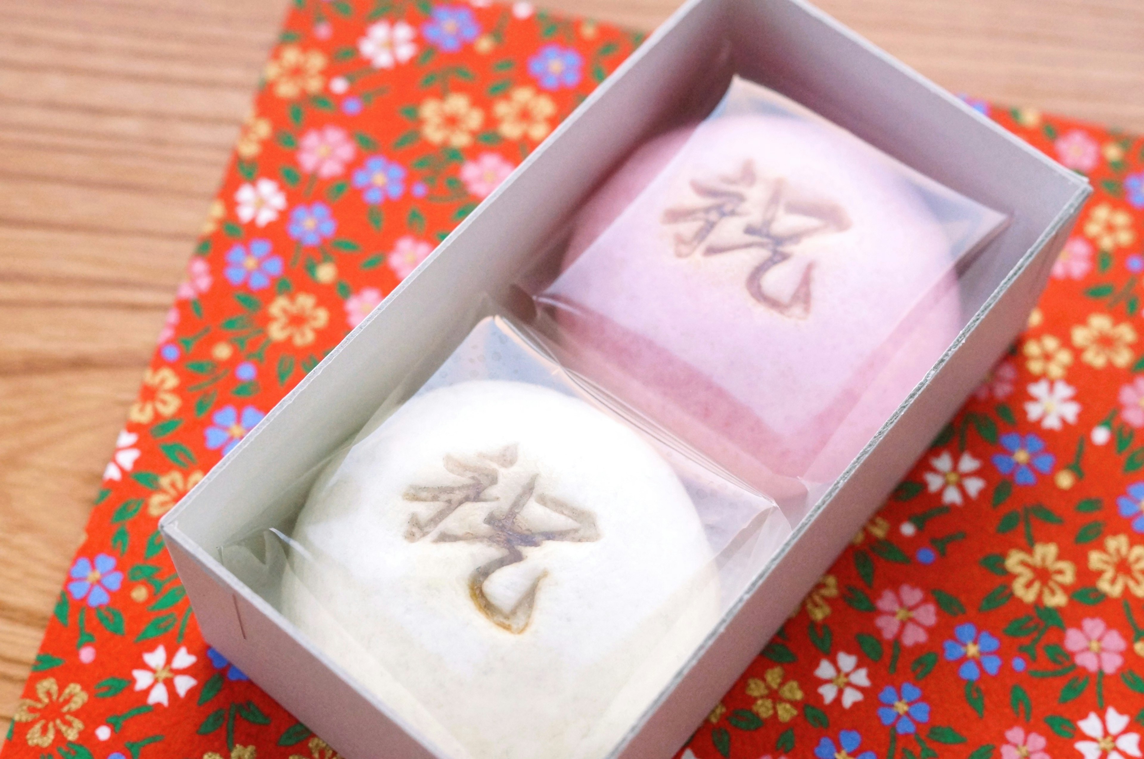 Two colorful mochi sweets in a box on a floral background