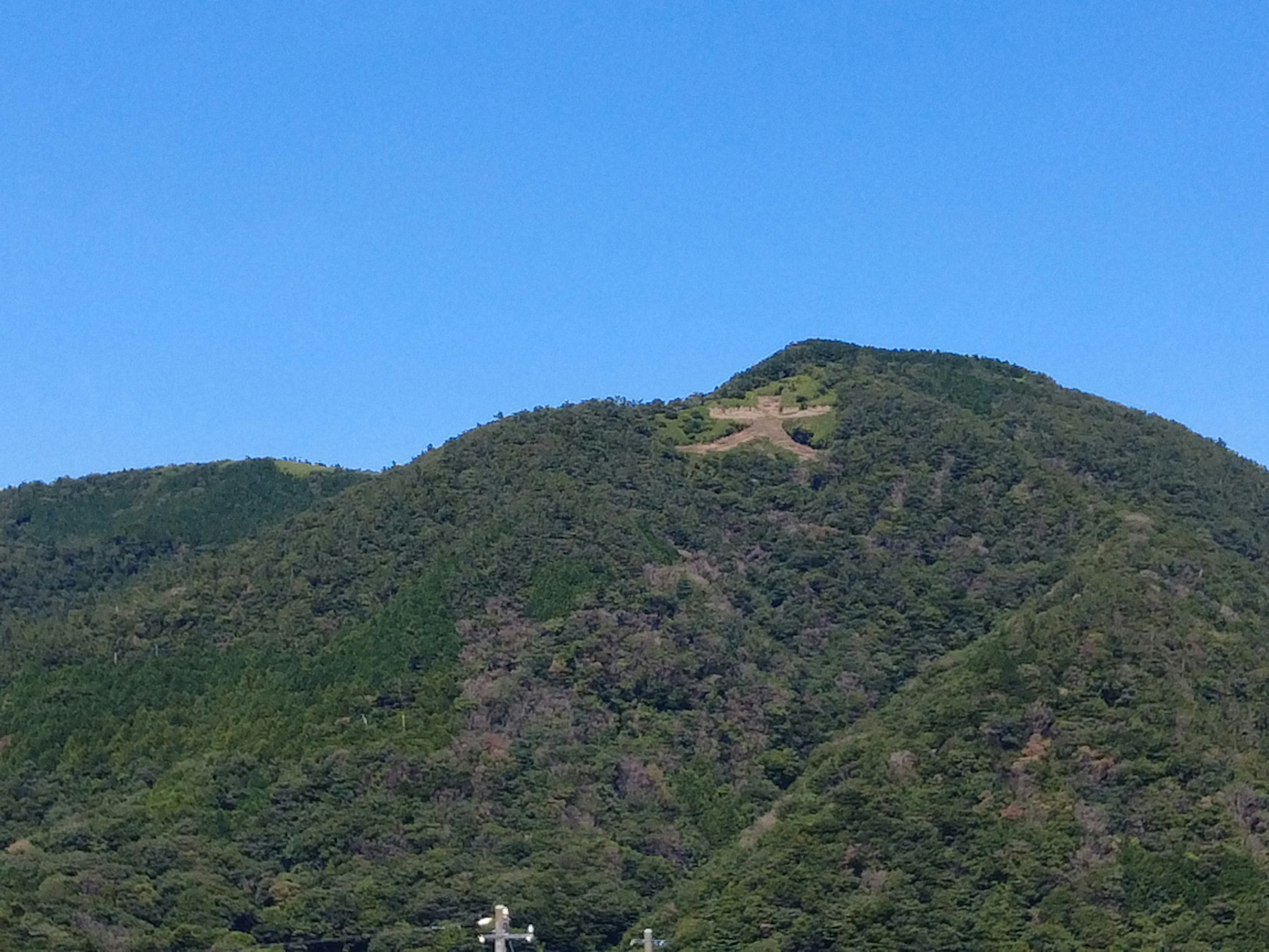 清澈蓝天下绿色山脉的美景，山顶可见小道