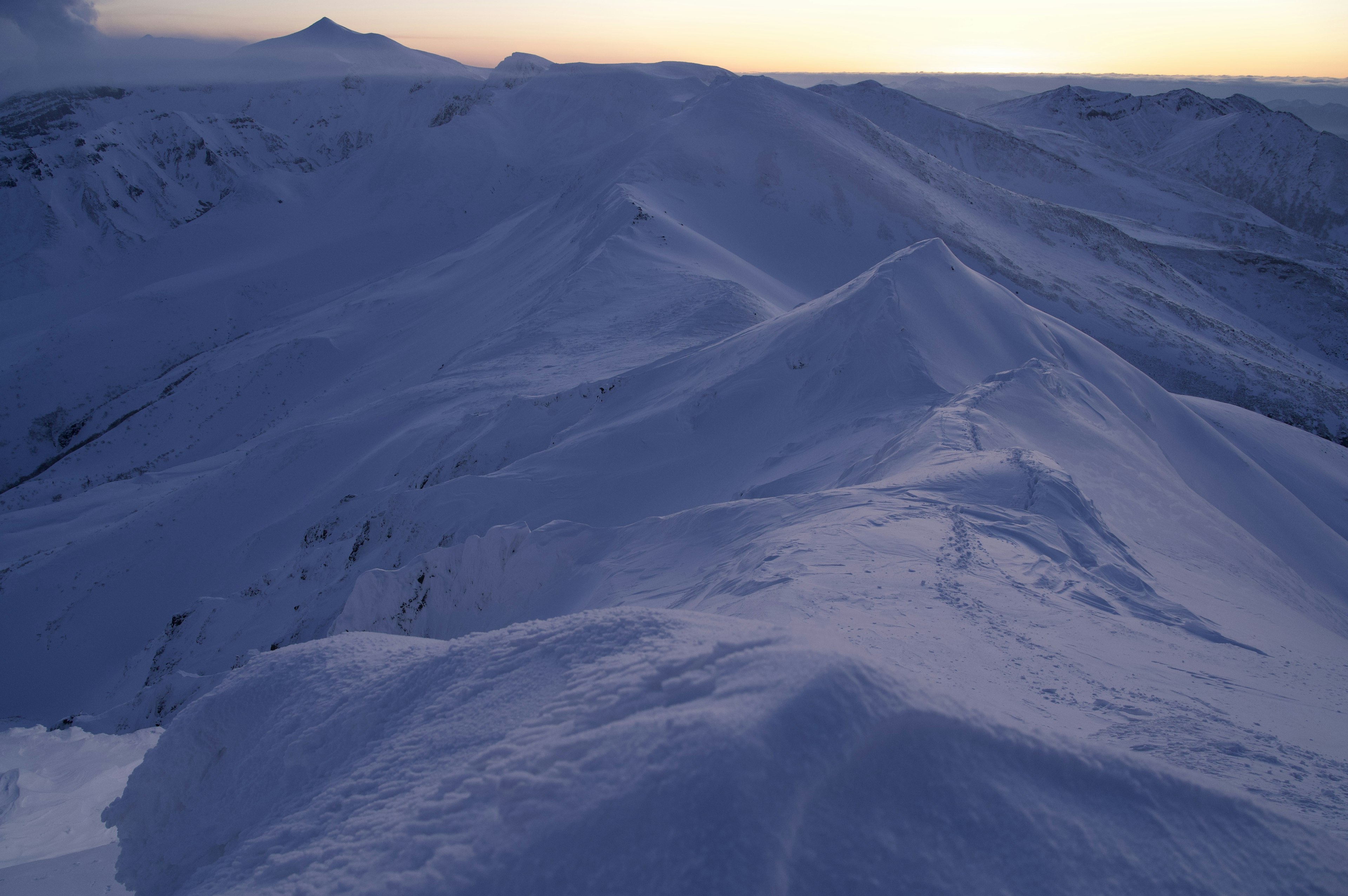 Paisaje montañoso cubierto de nieve con cielo al atardecer