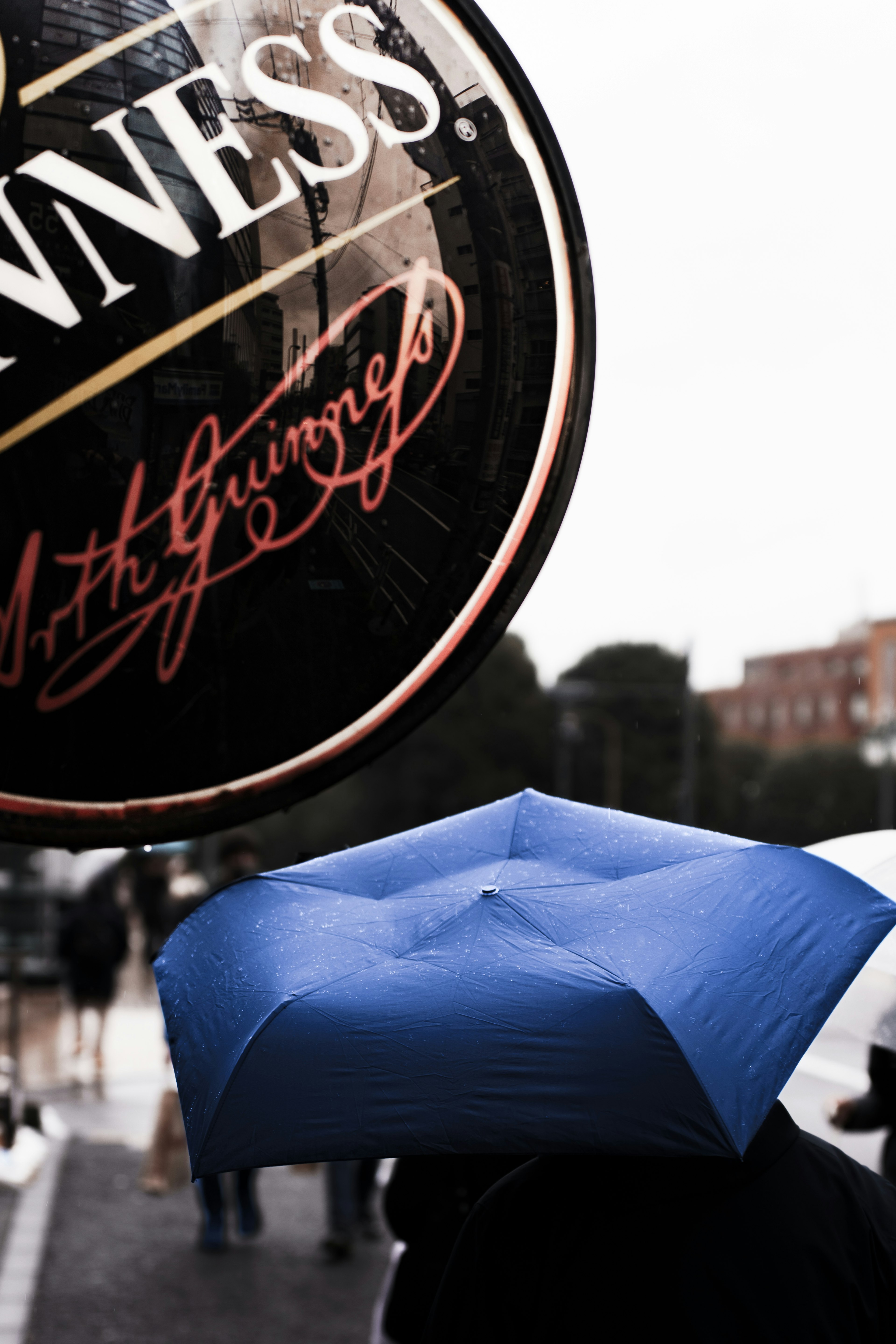 Ein blauer Regenschirm mit einem Guinness-Schild im Hintergrund