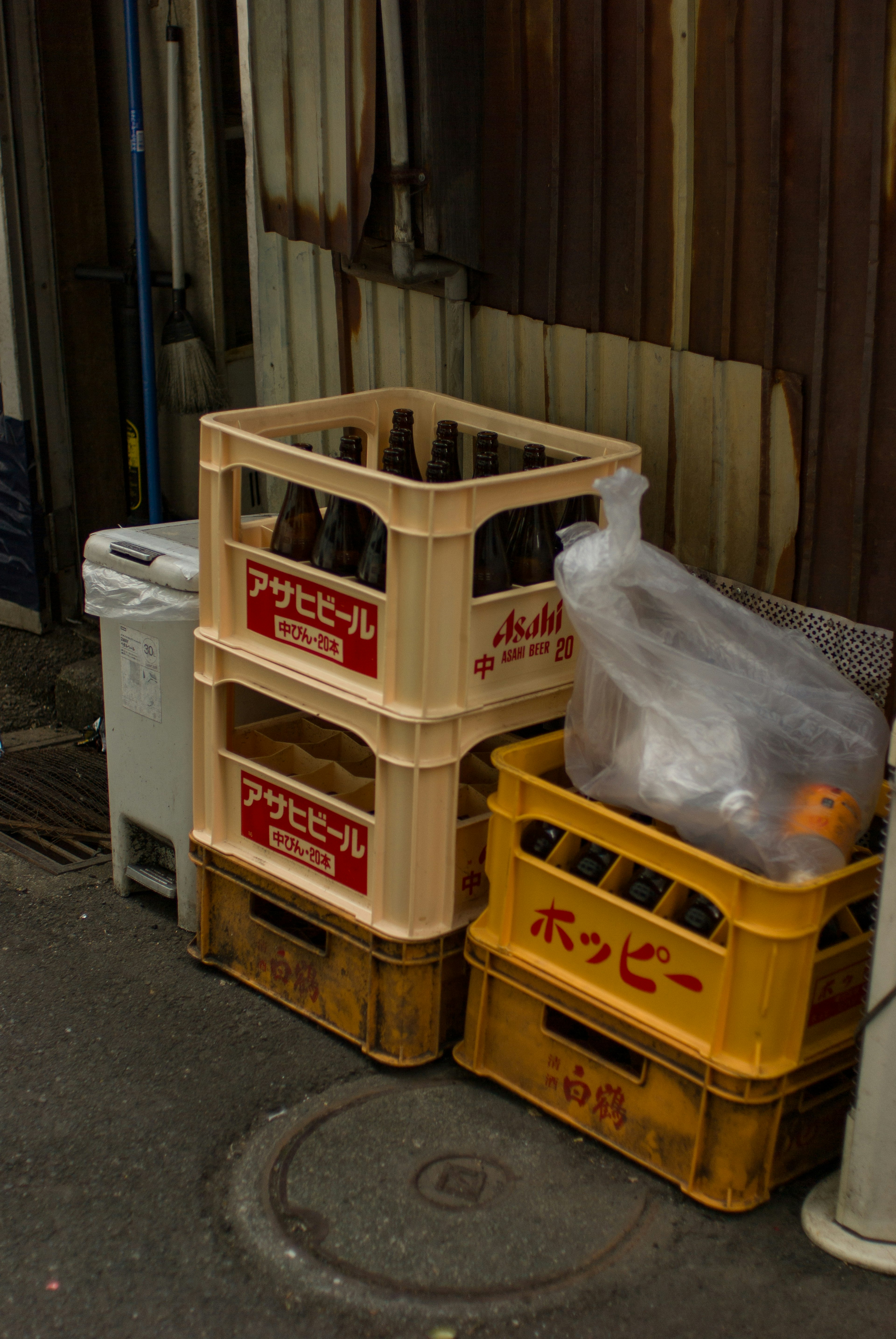 Caisses de bière empilées et un sac poubelle dans une ruelle