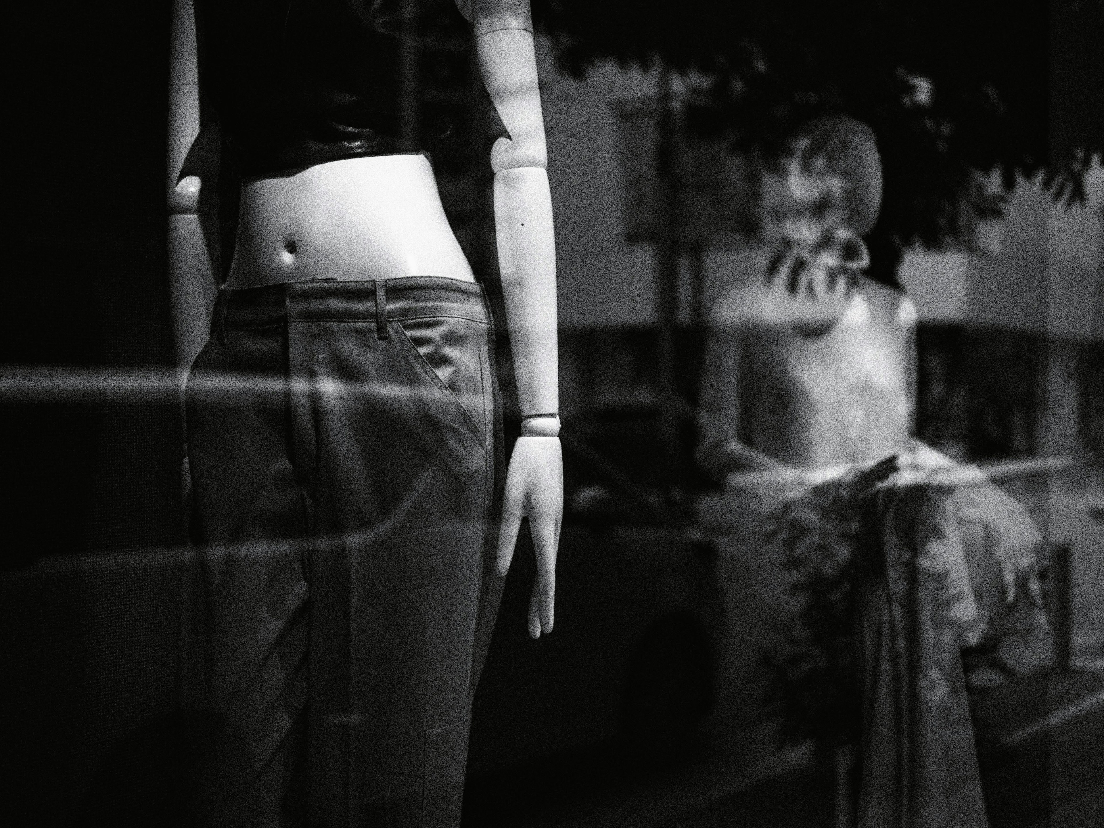 Mannequin torso displayed in a shop window with another mannequin in the background