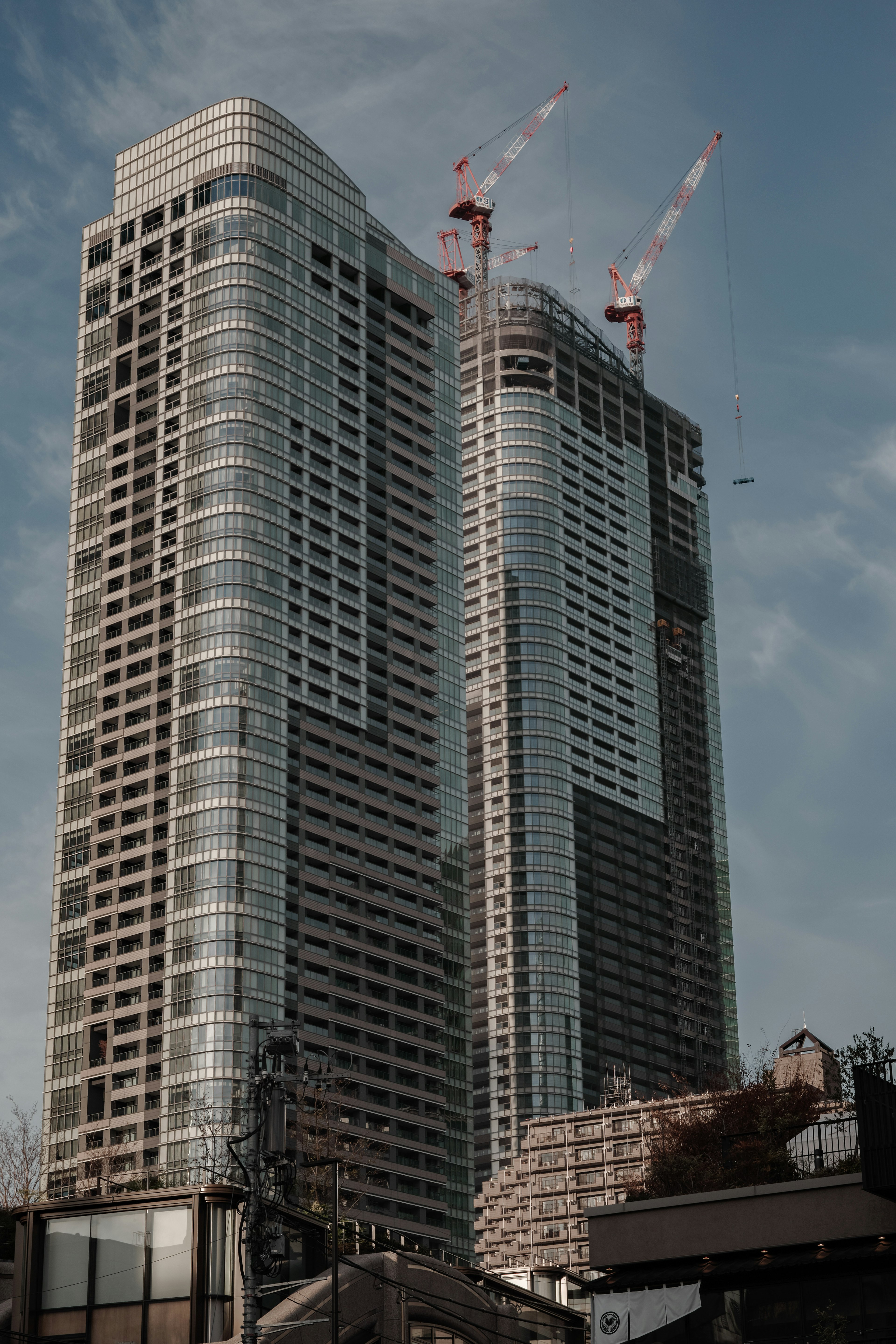 Construction site of tall buildings with modern design against a blue sky featuring cranes