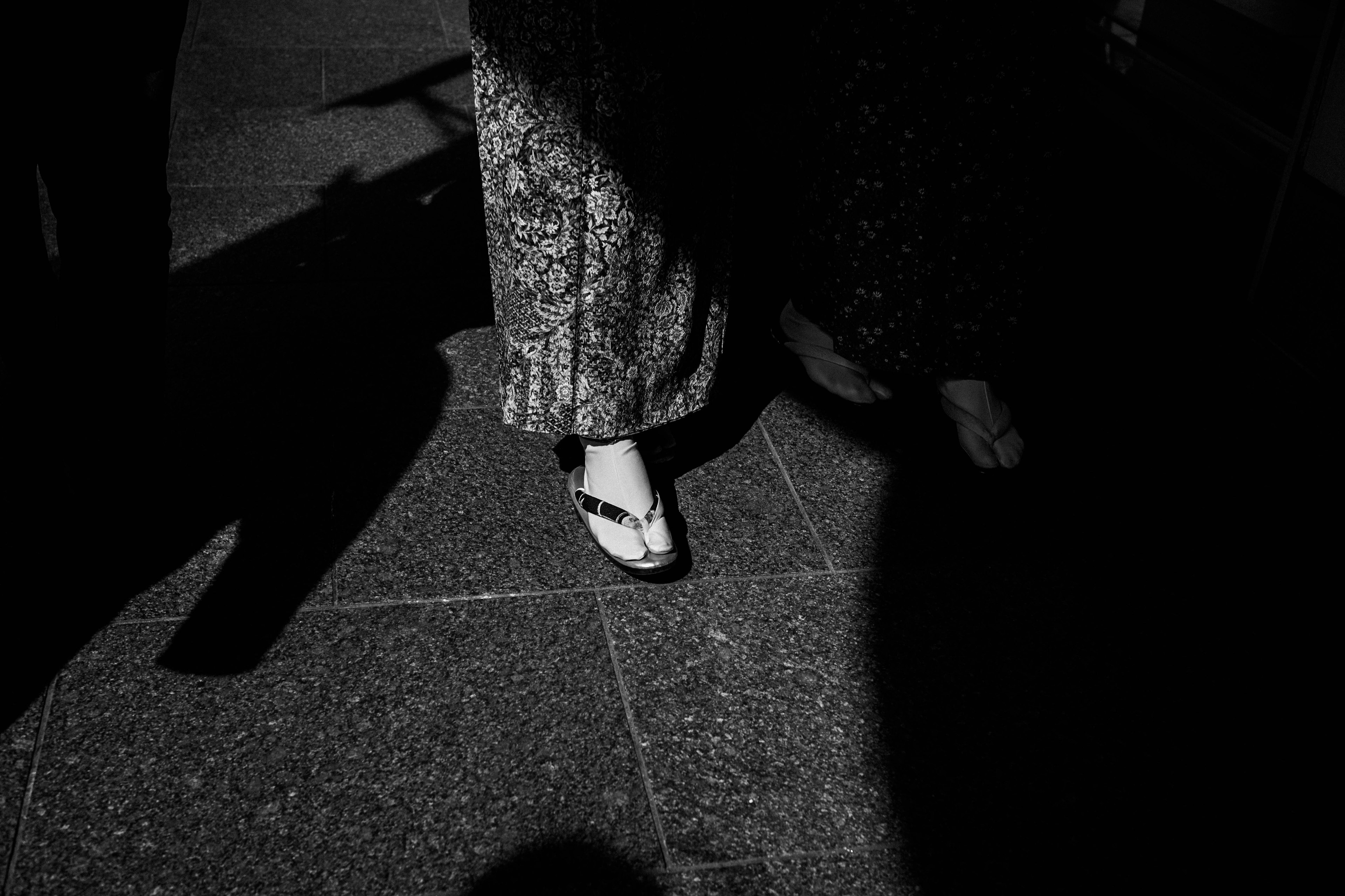 Close-up of a woman's feet walking in black and white patterned pants and white shoes