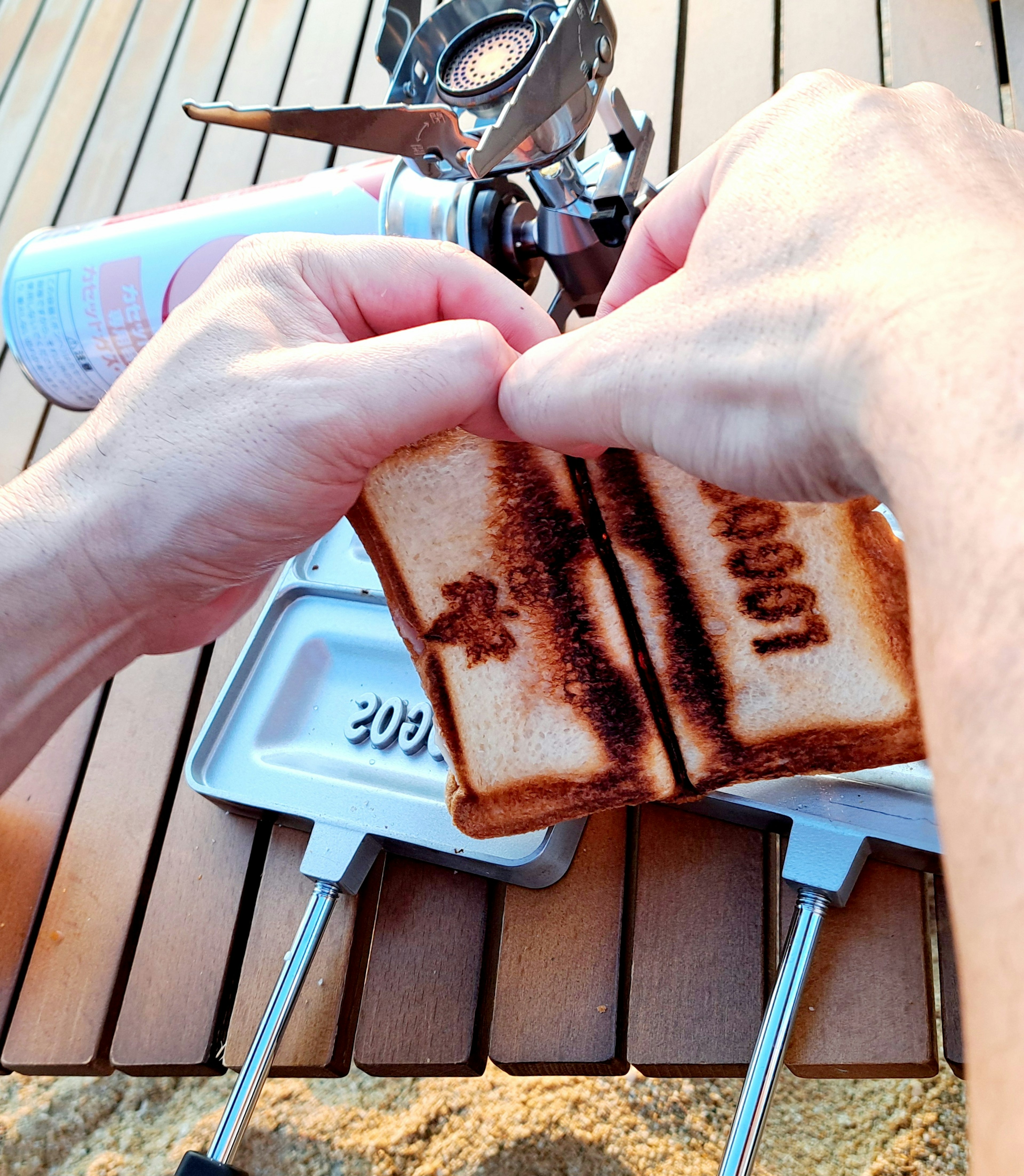 Mani che separano del pane tostato con un motivo di marchio su un tavolo di legno