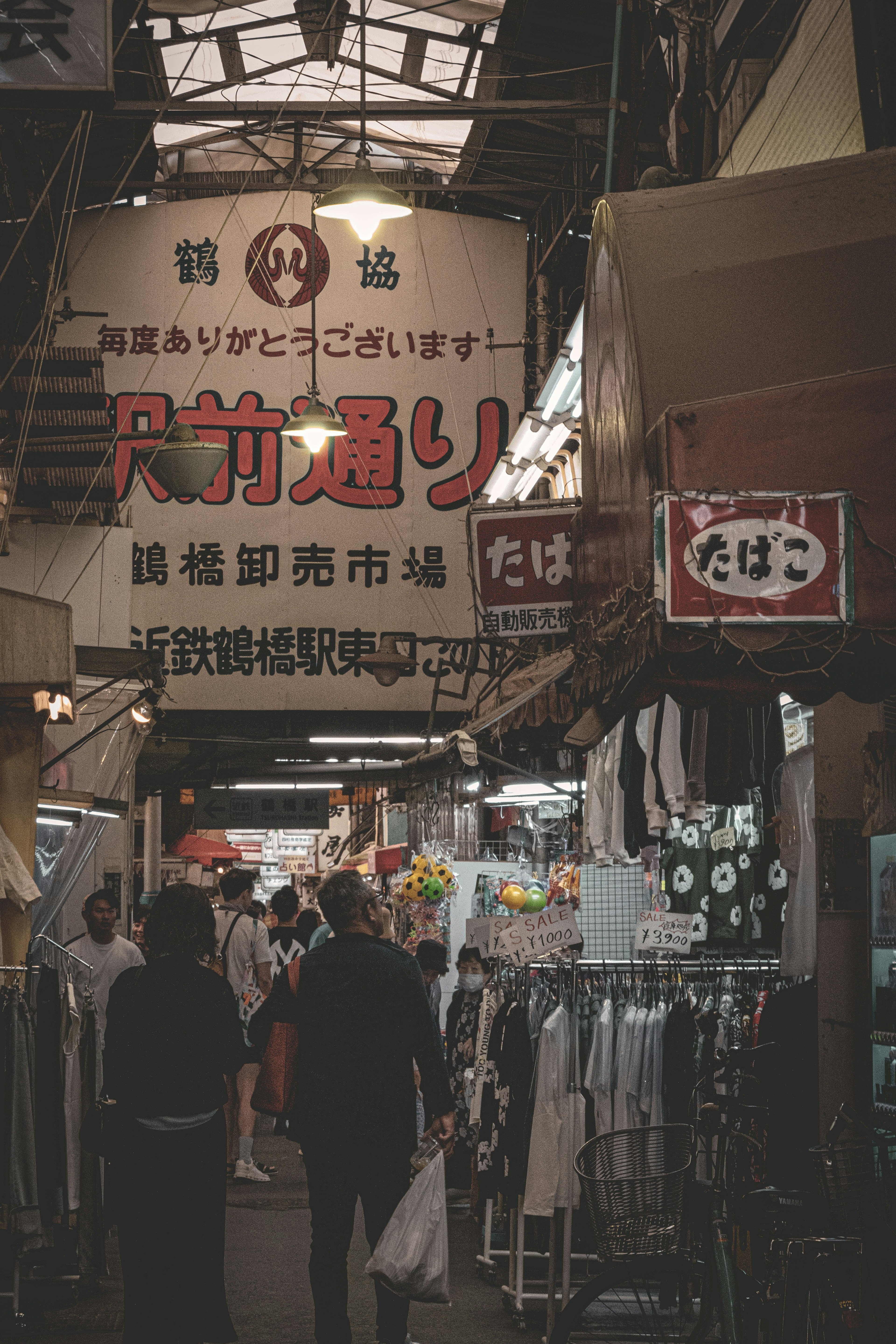 人们在日本市场街道上走动，上方有标志