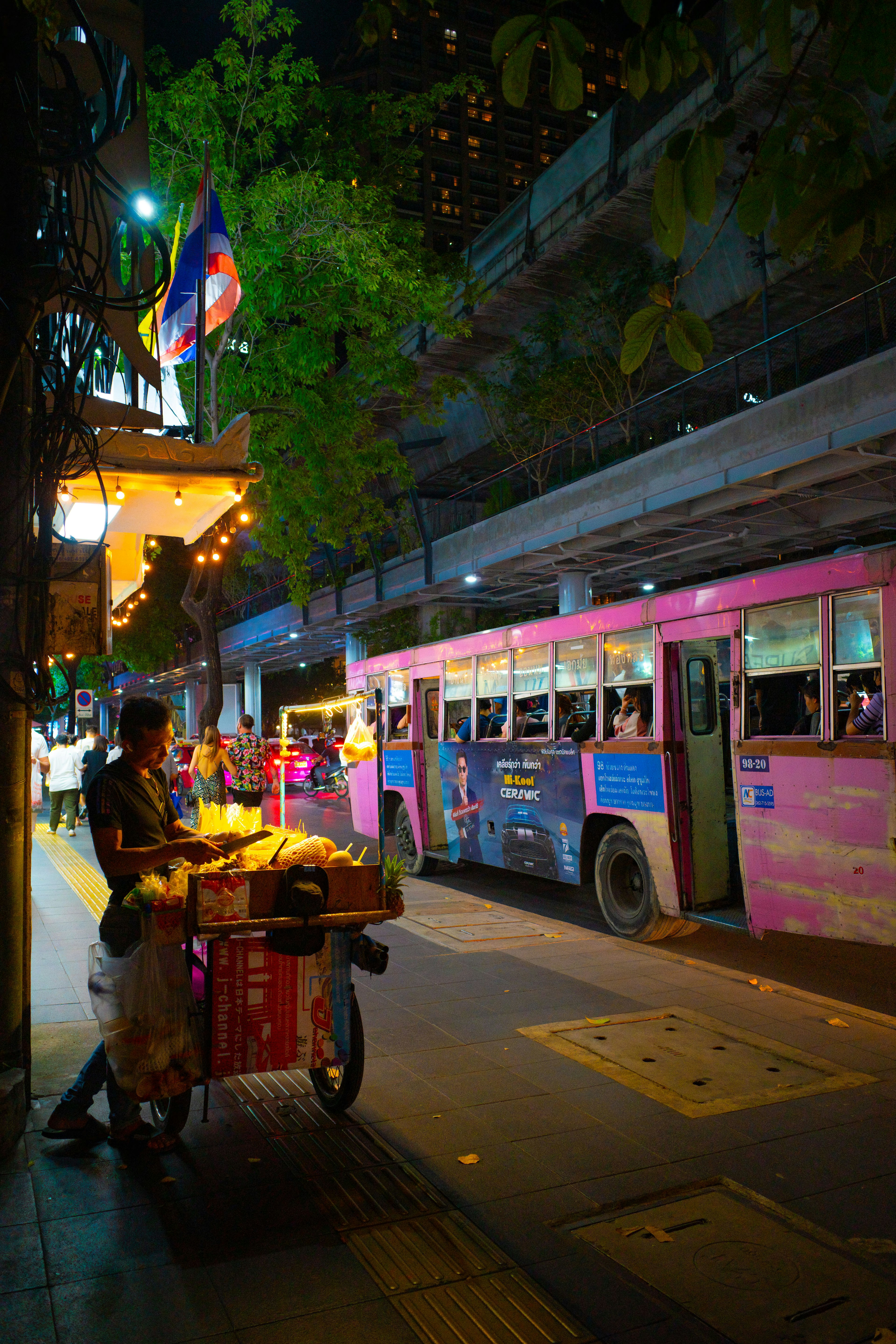 Scène nocturne avec un bus rose et un vendeur de rue