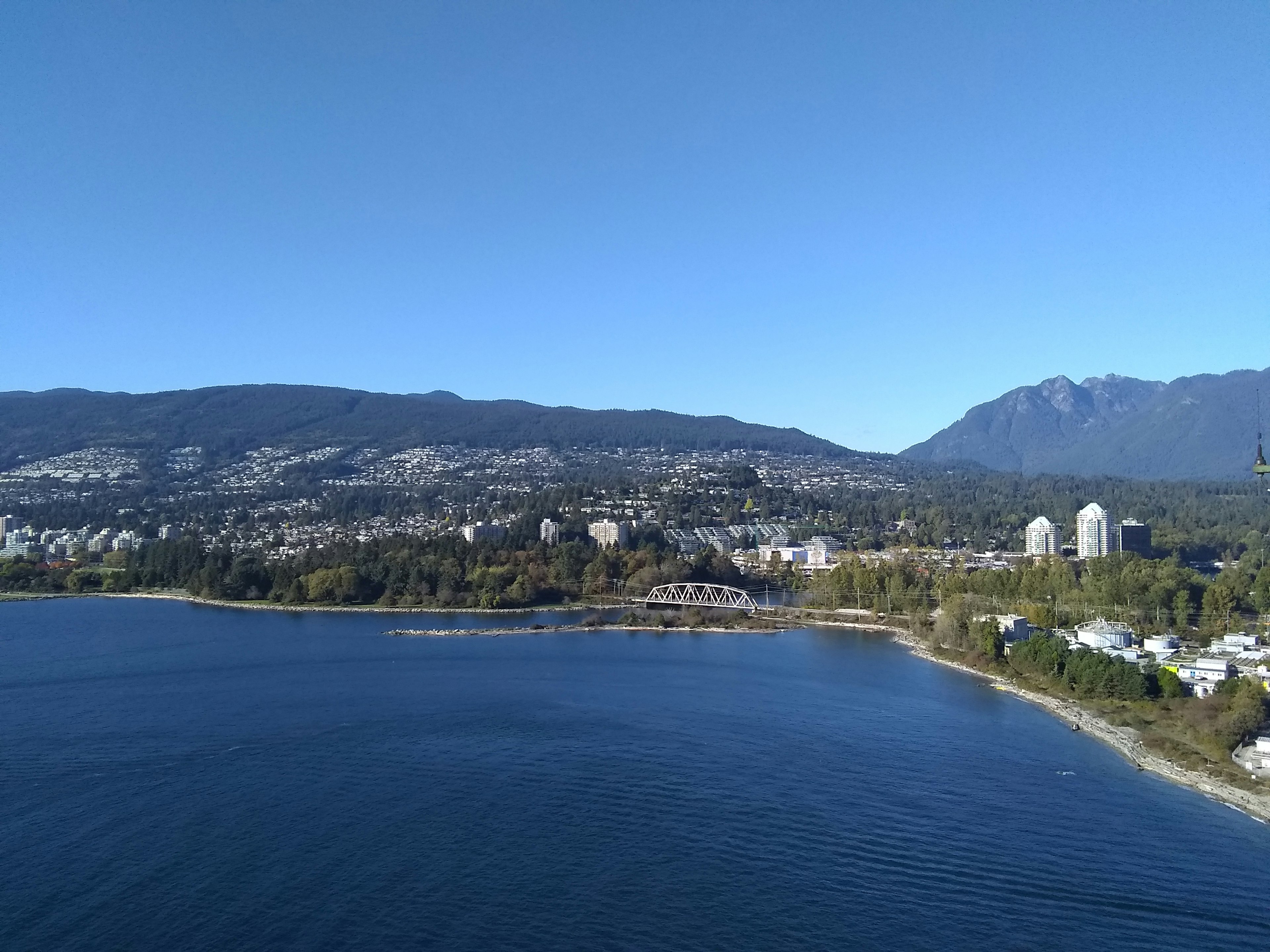 Vista escénica de montañas y ciudad a lo largo de un mar tranquilo bajo un cielo despejado