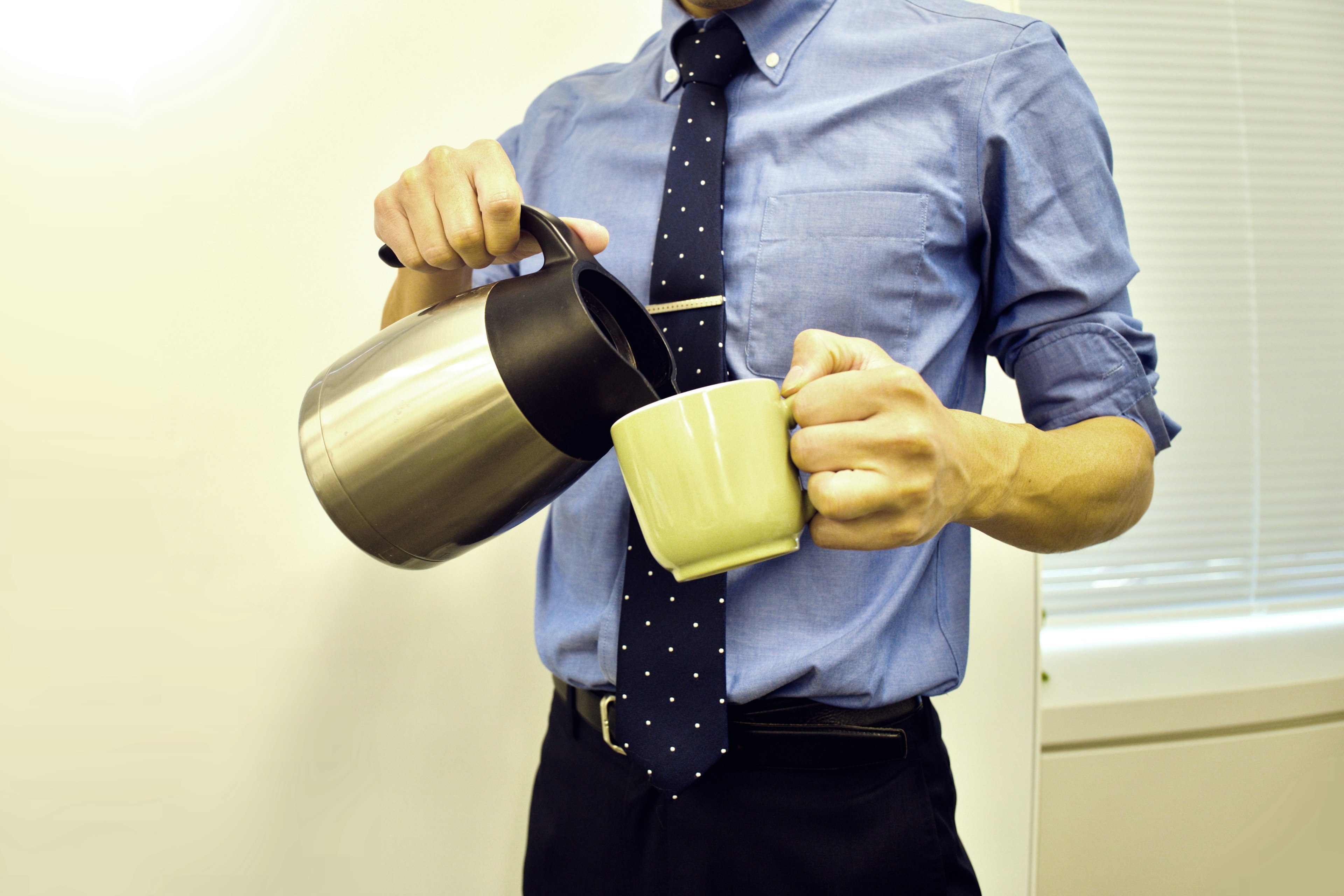 Ein Mann im Anzug, der Kaffee in eine Tasse gießt