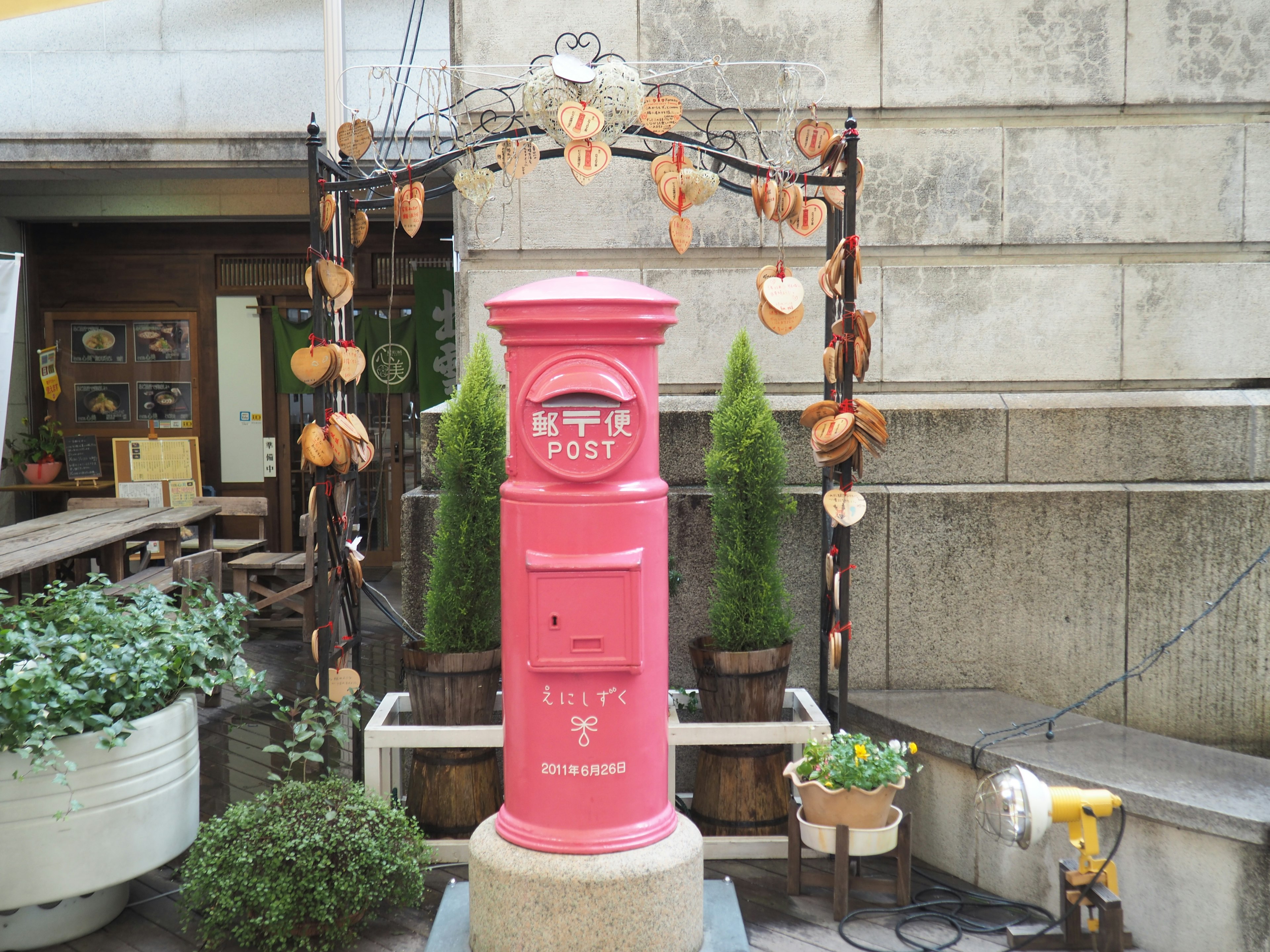 Pink mailbox surrounded by greenery and decorative elements