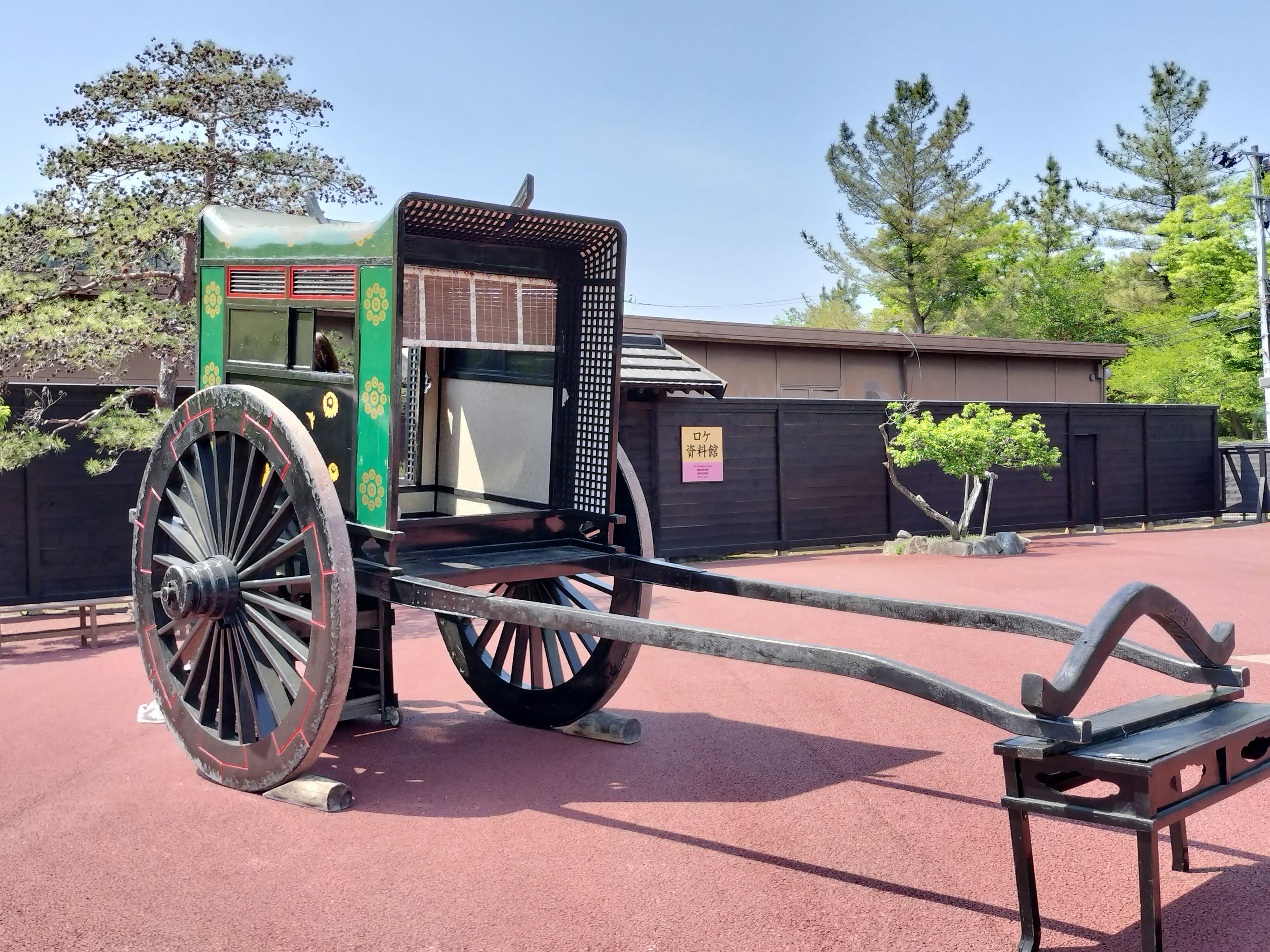 Carrozza tradizionale trainata da cavalli con decorazioni verdi e nere esposta in un parco