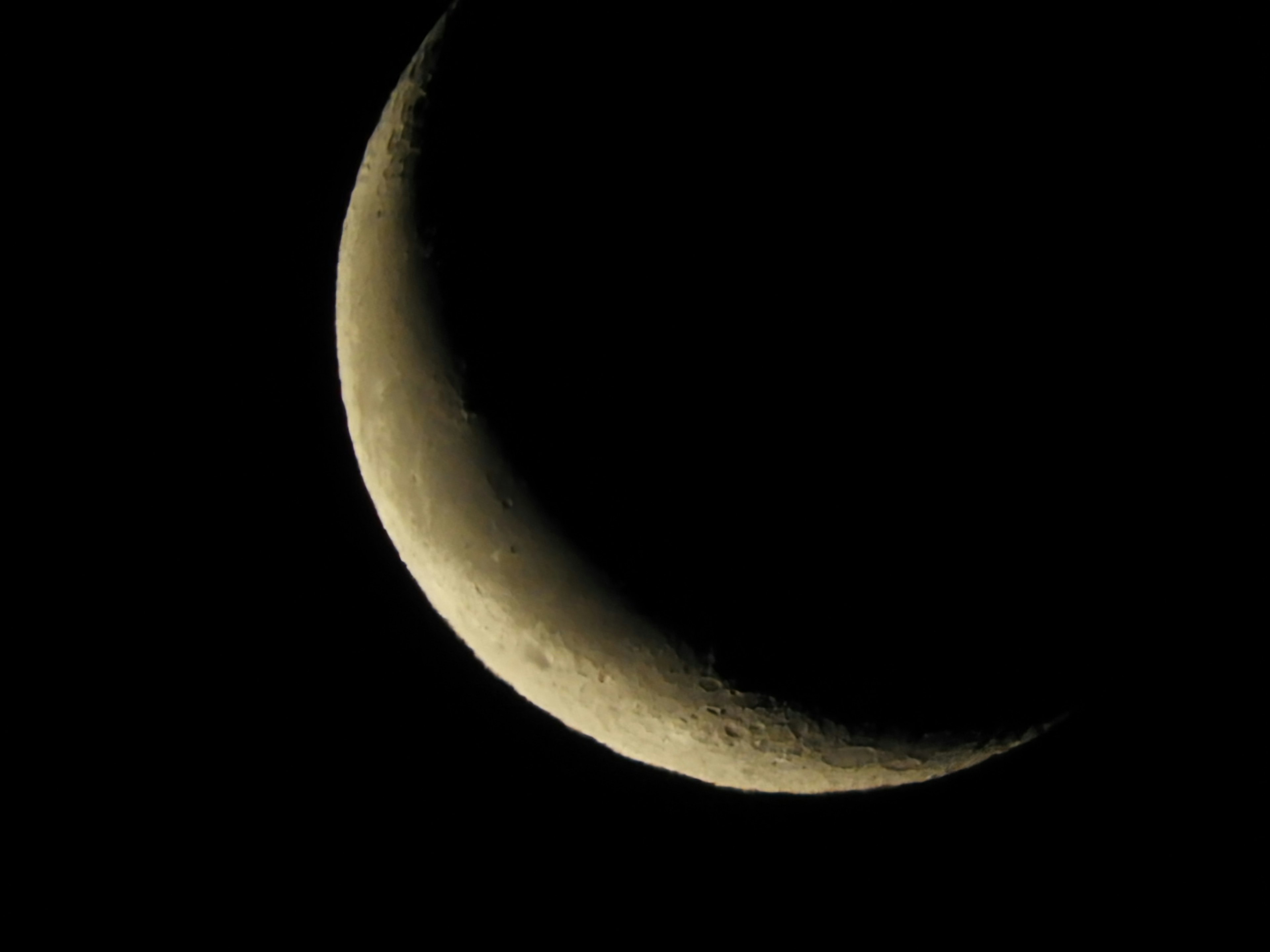 Dünner zunehmender Mond vor dunklem Hintergrund