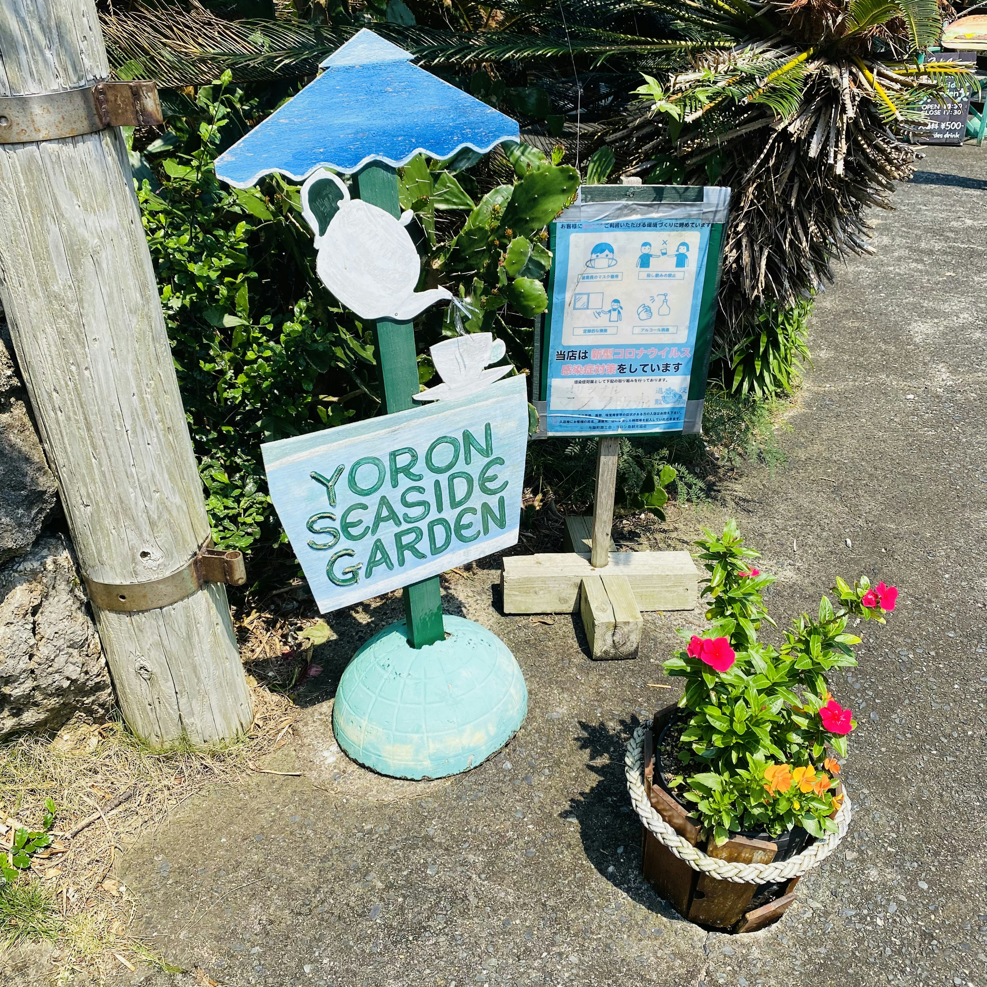 ヨロンシーサイドガーデンの看板と花の鉢植え