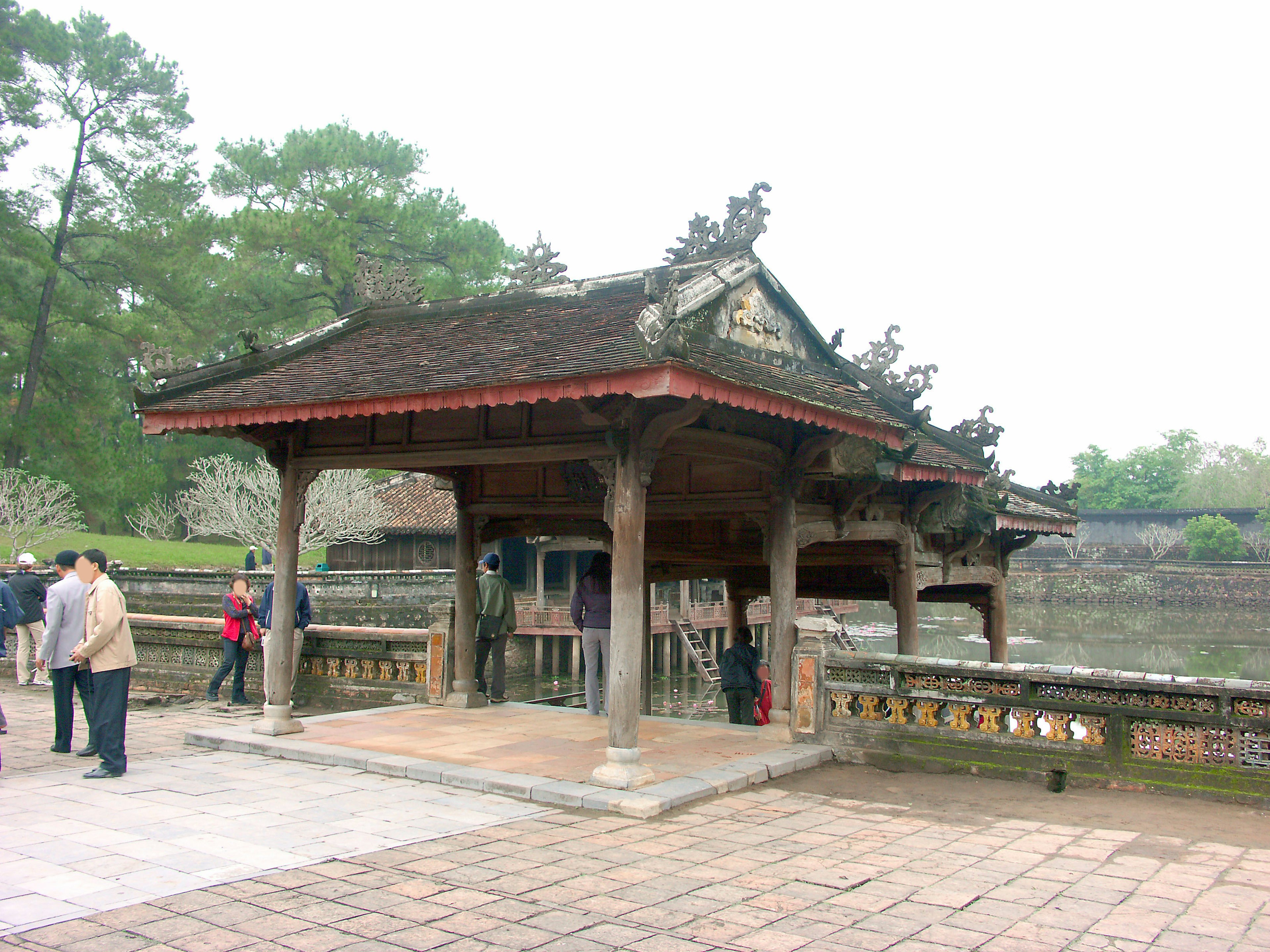 Pavillon en bois traditionnel au bord de l'eau entouré de verdure