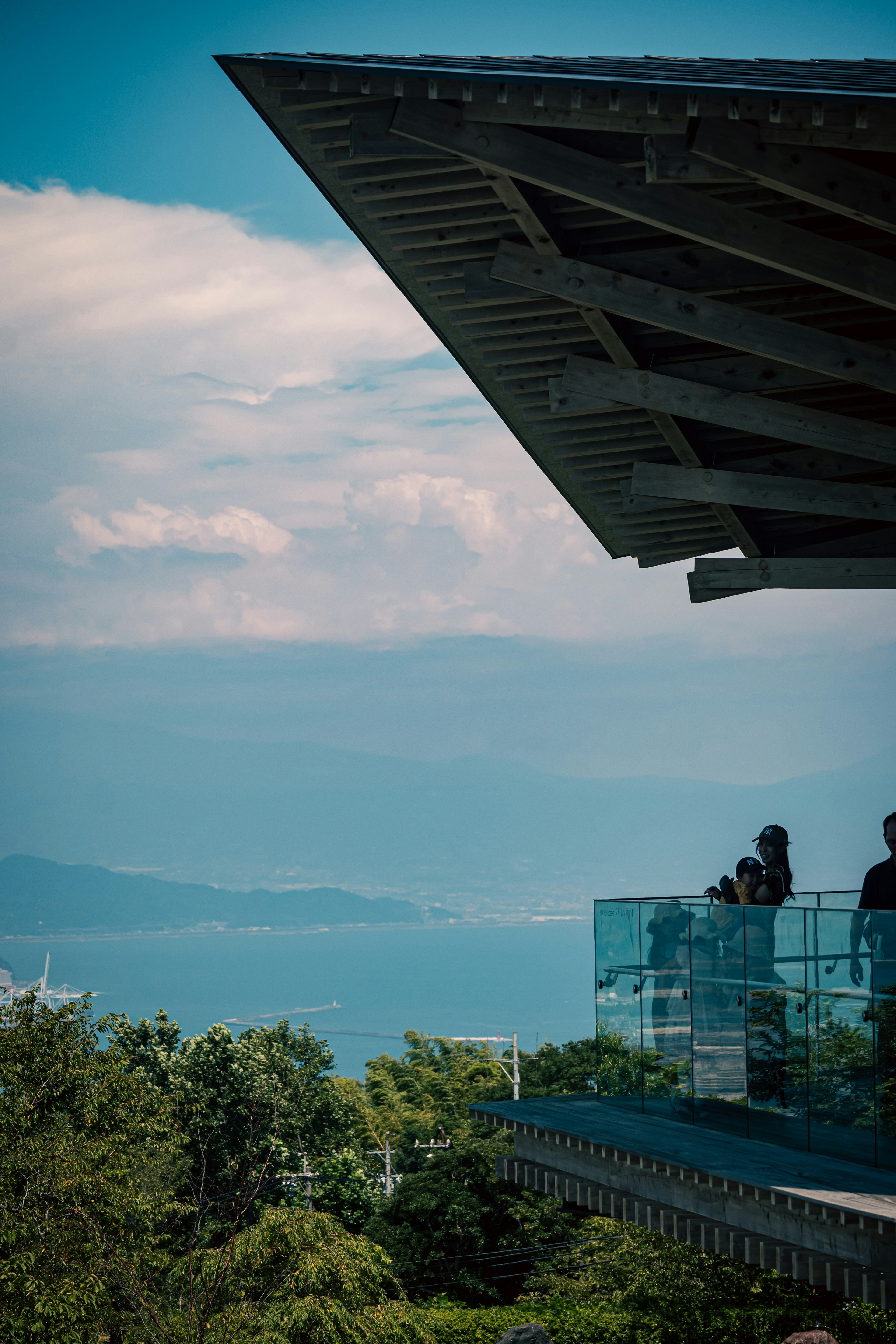 Tetto di un edificio moderno con un balcone che si affaccia su una bella vista del mare e persone in piedi