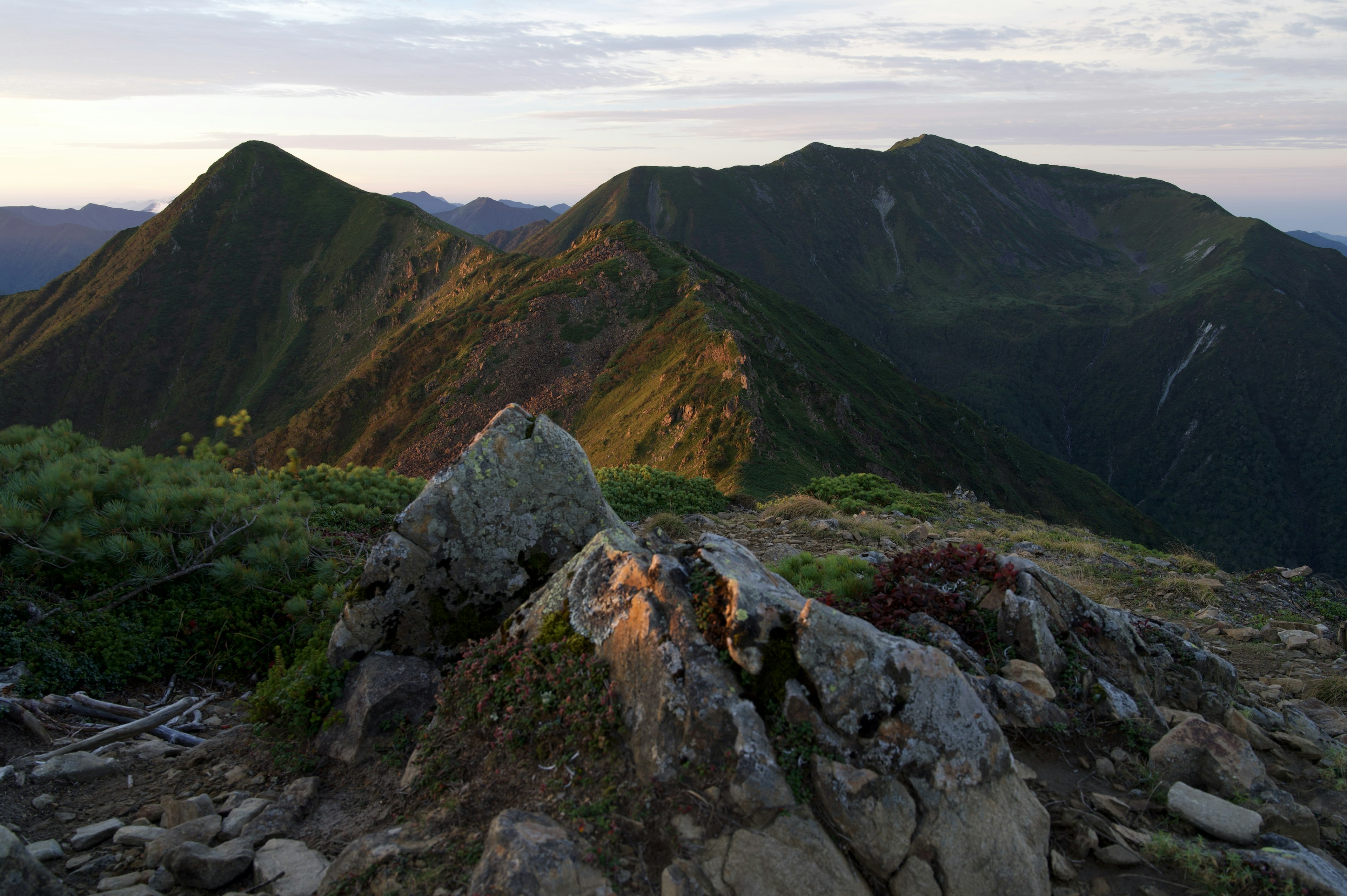 Vue depuis un sommet de montagne avec des montagnes vertes et des rochers