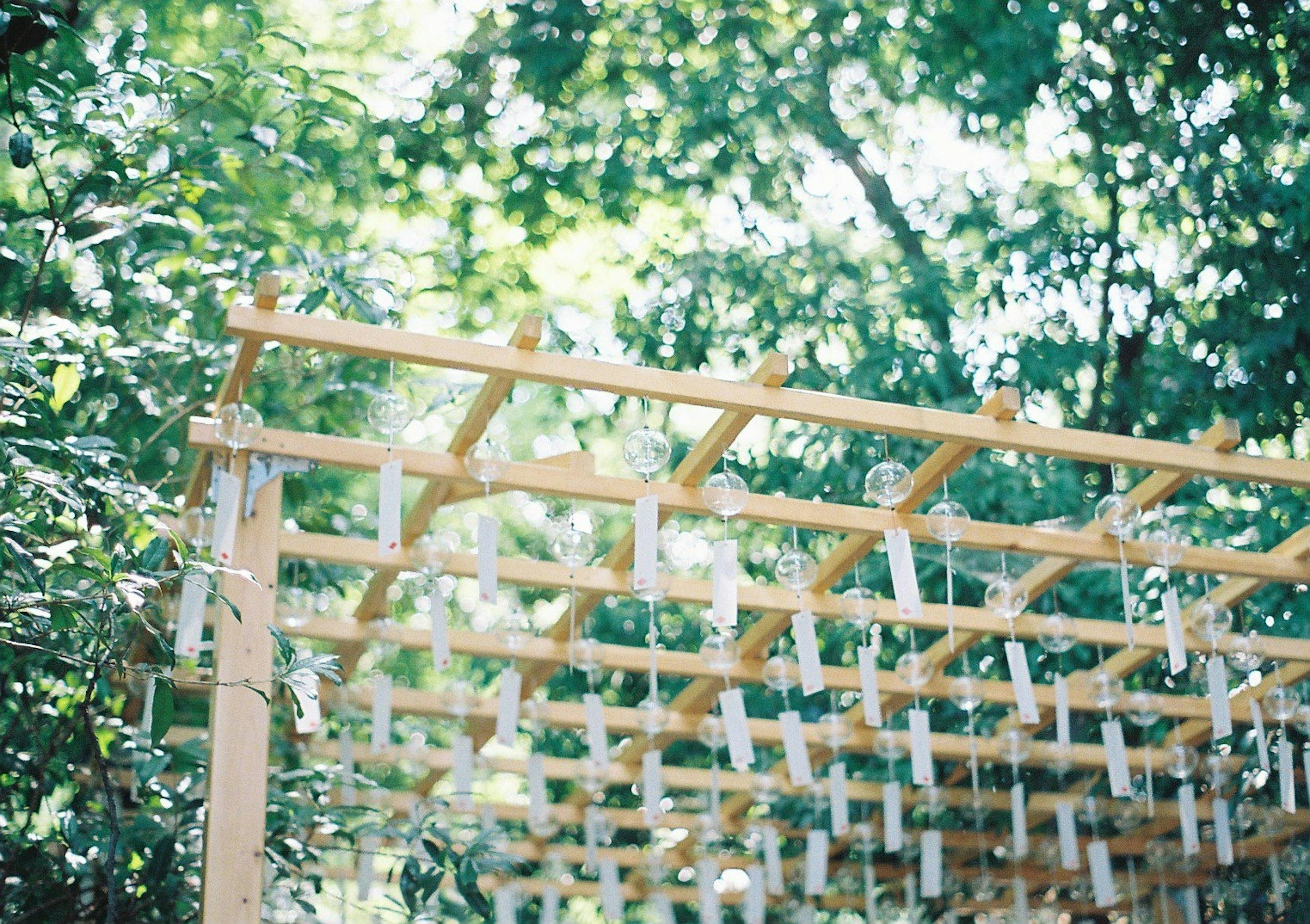 Wooden wind chime rack against a lush green backdrop