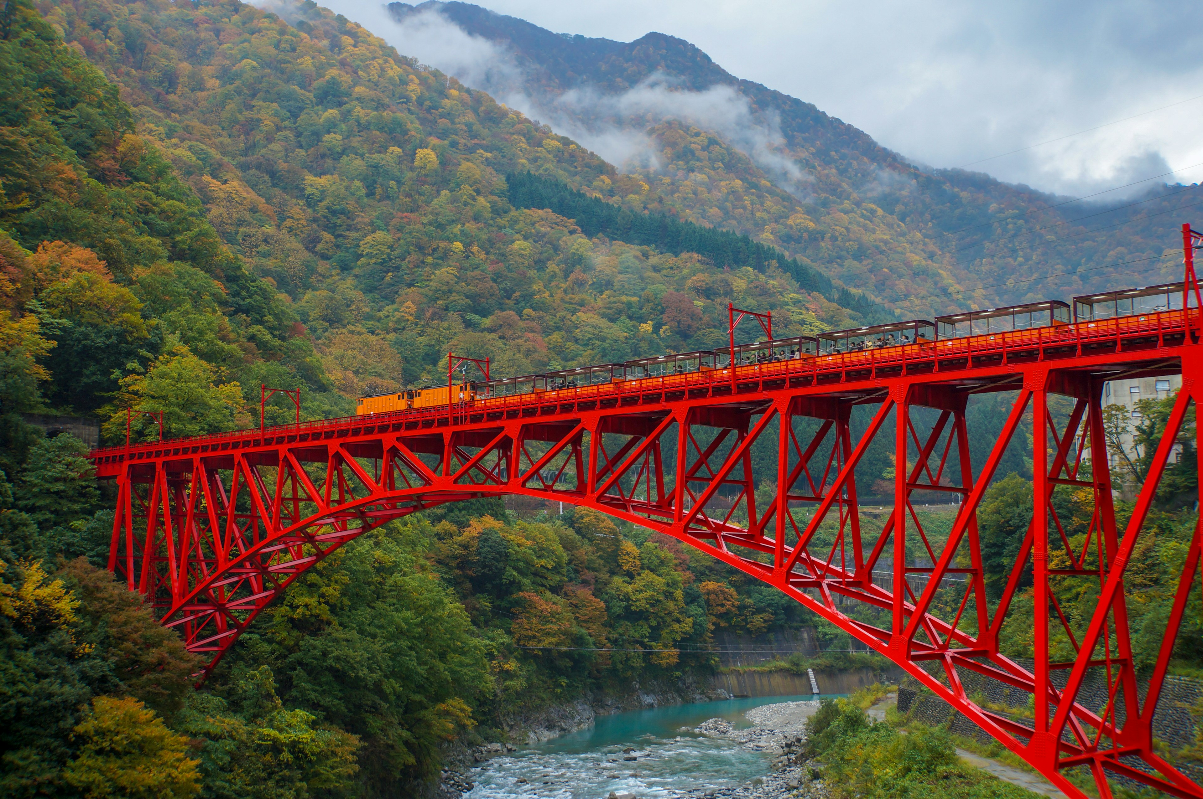 赤いアーチ型の橋が色とりどりの山々に囲まれている風景