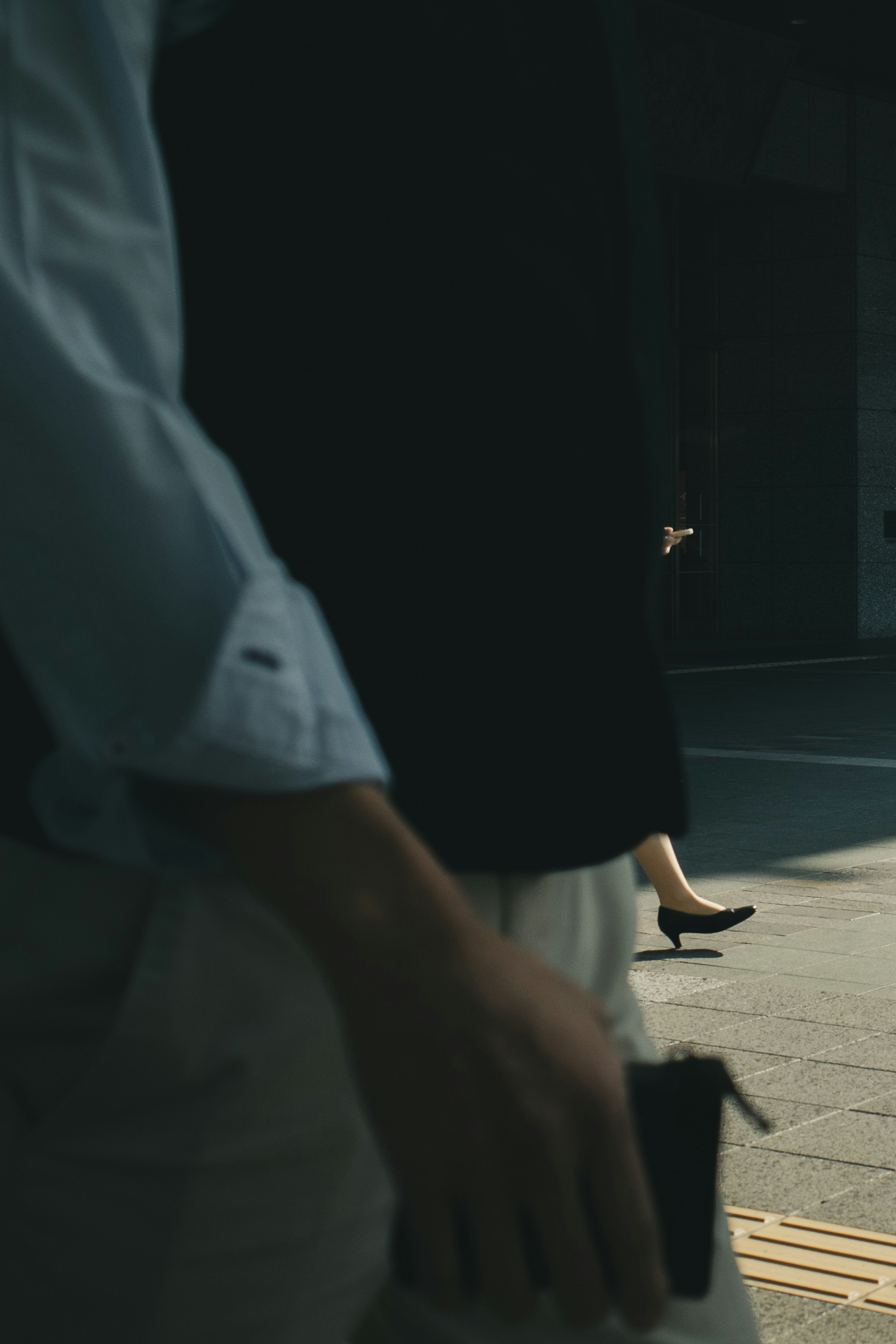 Silhouettes of people walking in the street with a woman in high heels