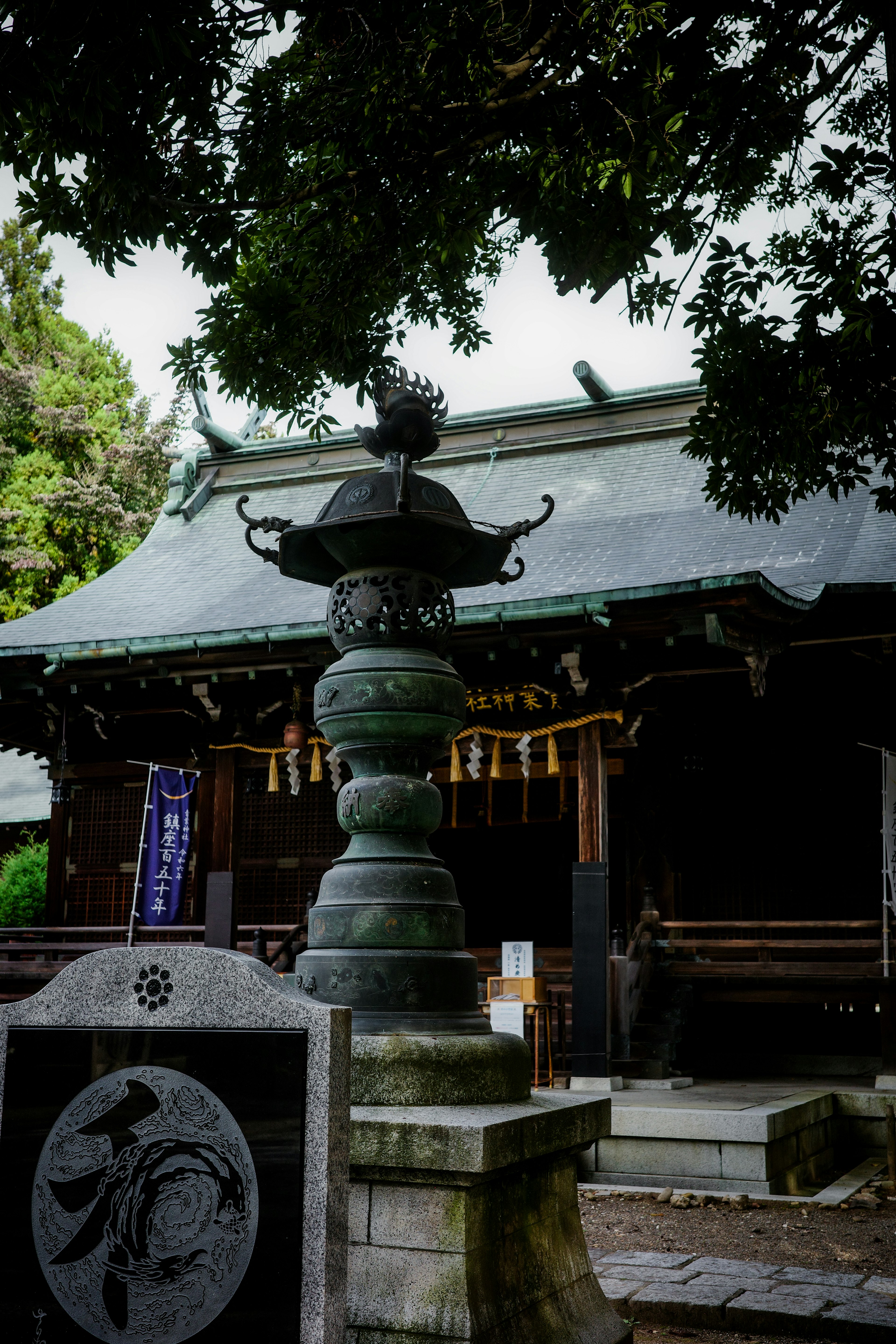 神社の前にある石の燈籠と屋根の上にいる鳥