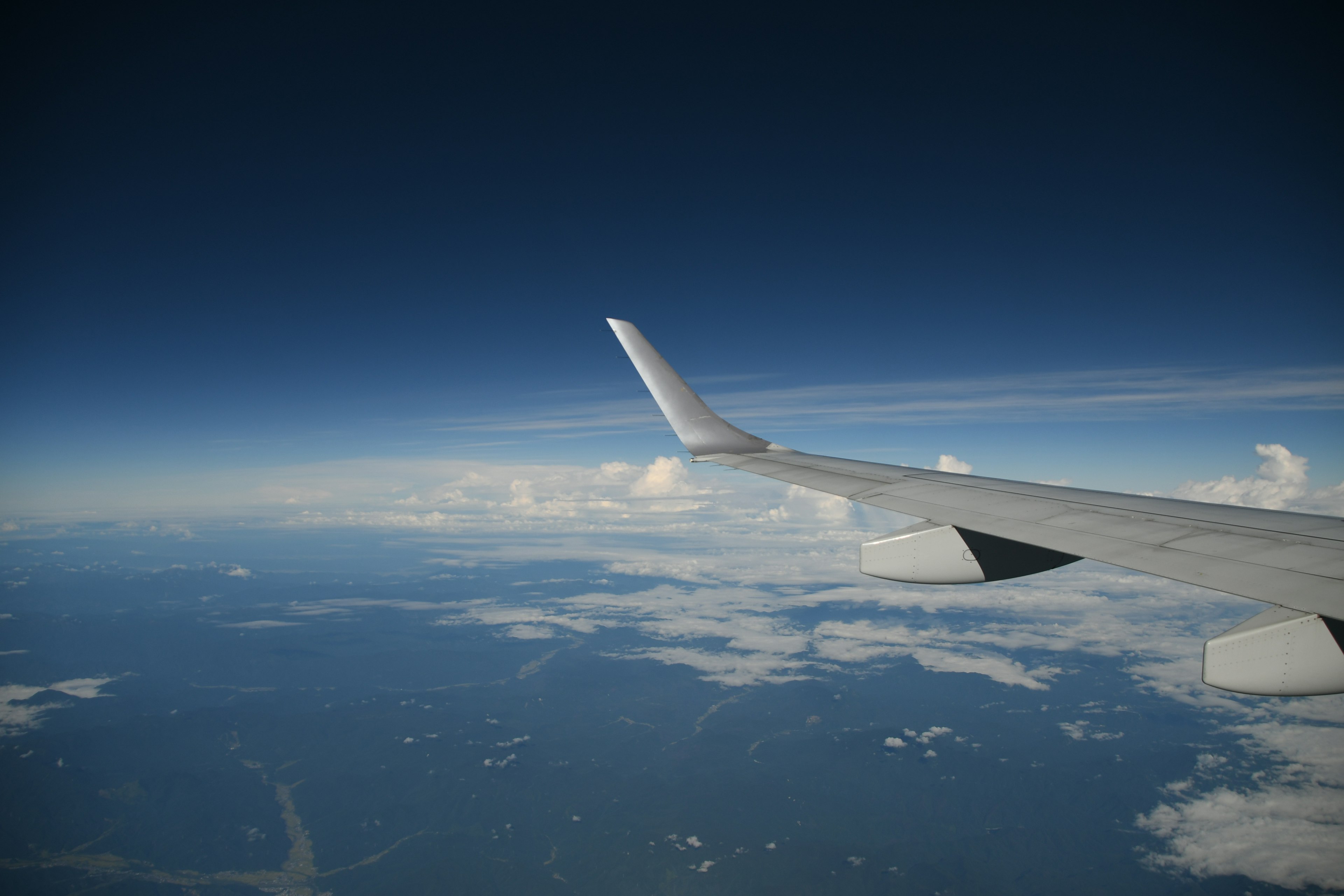 Airplane wing against a blue sky and clouds