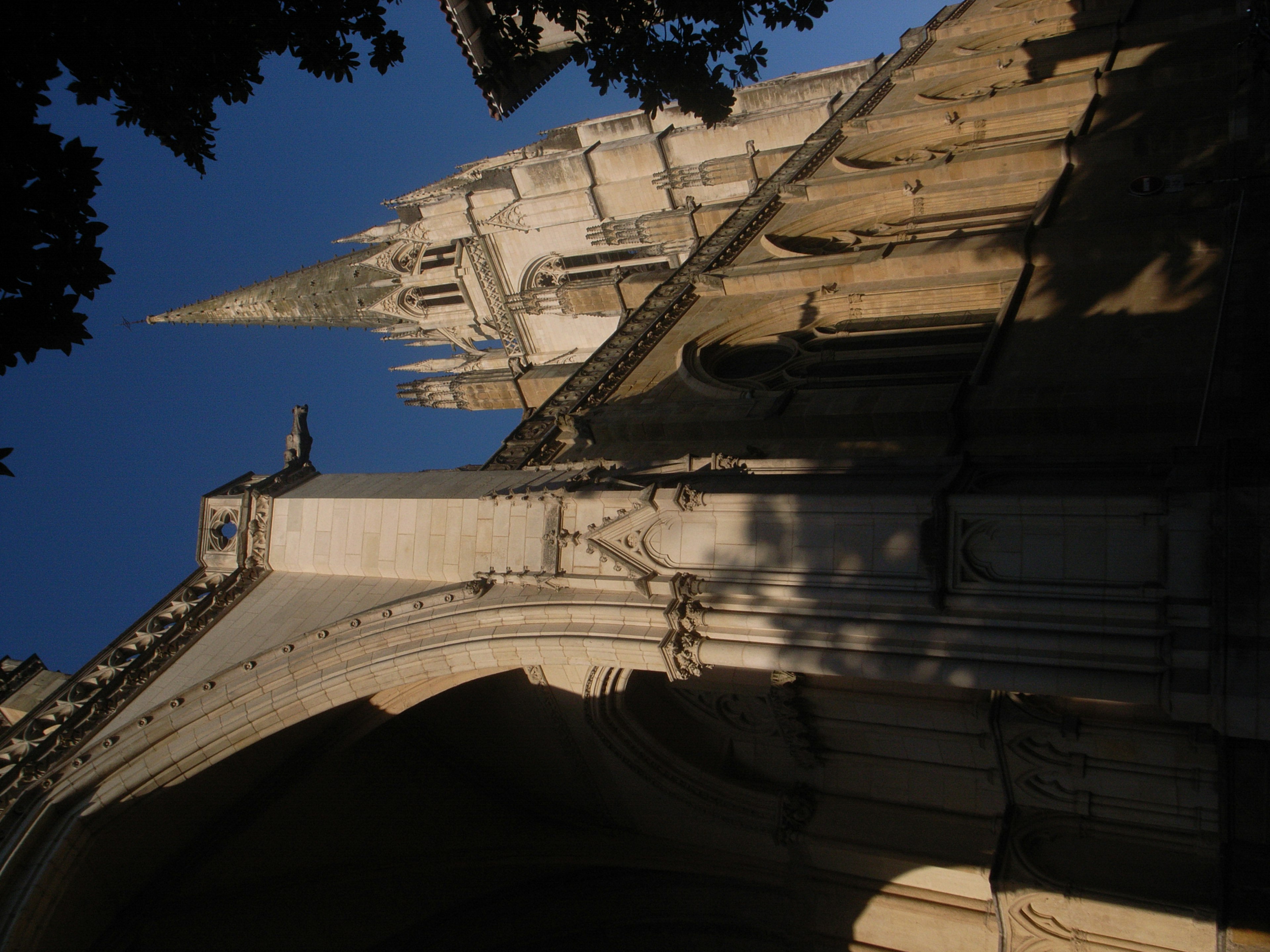 Gothic architecture with pointed spires and arched entryway against a blue sky