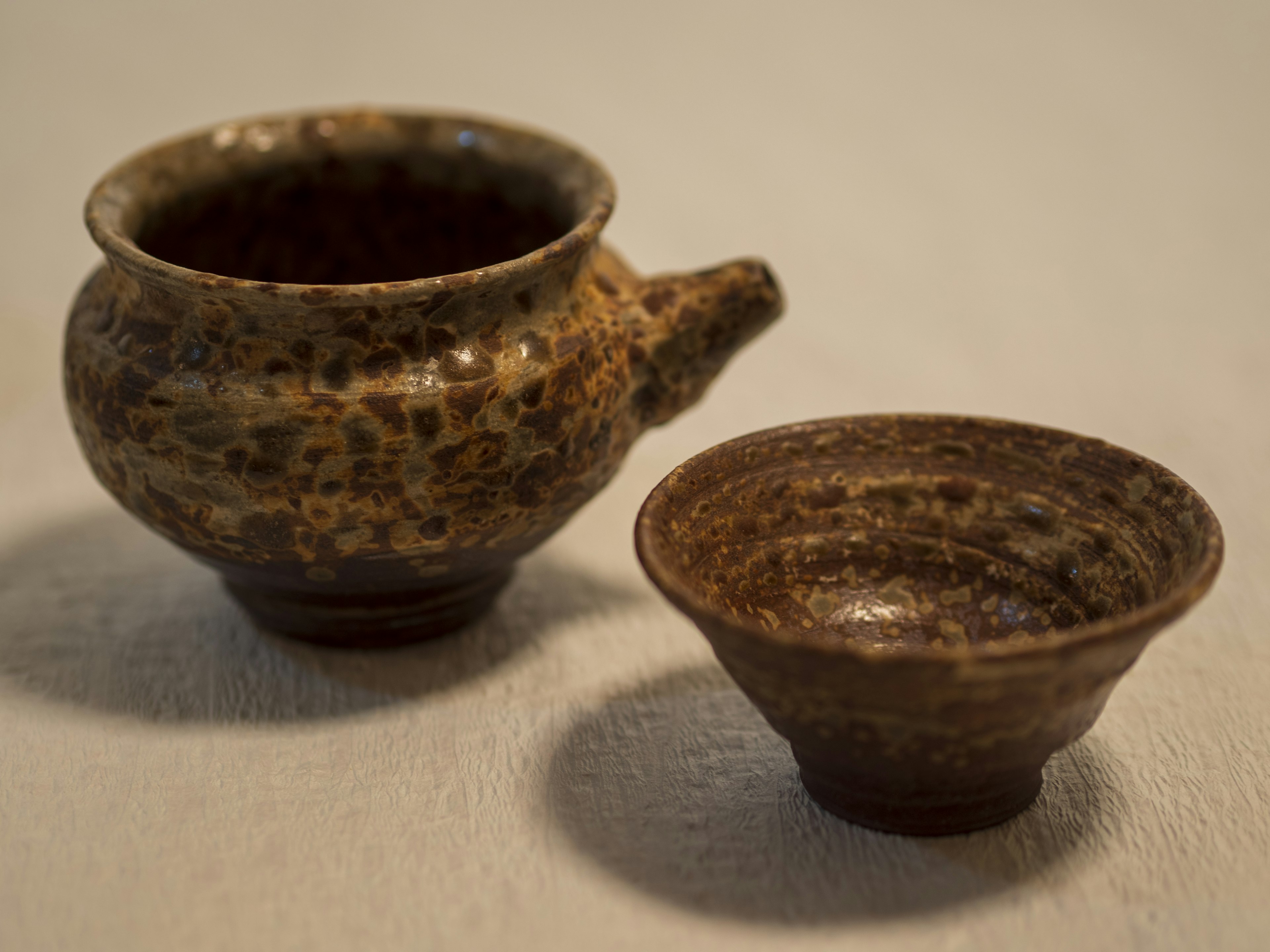 A tea set featuring a pot with a spout and a small bowl