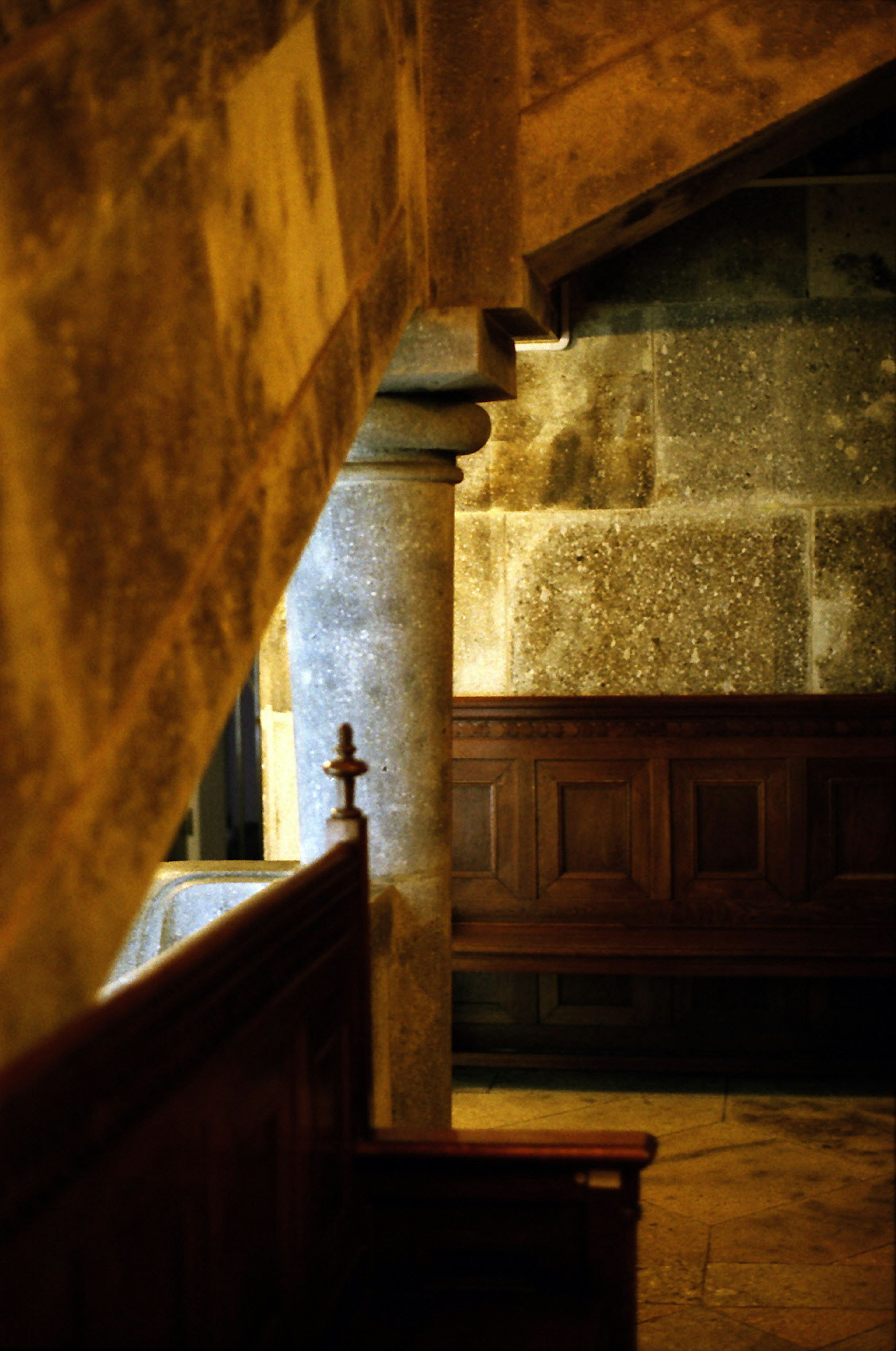 Innenecke mit einem Steinsäule und einer alten Holzbank unter einer Treppe