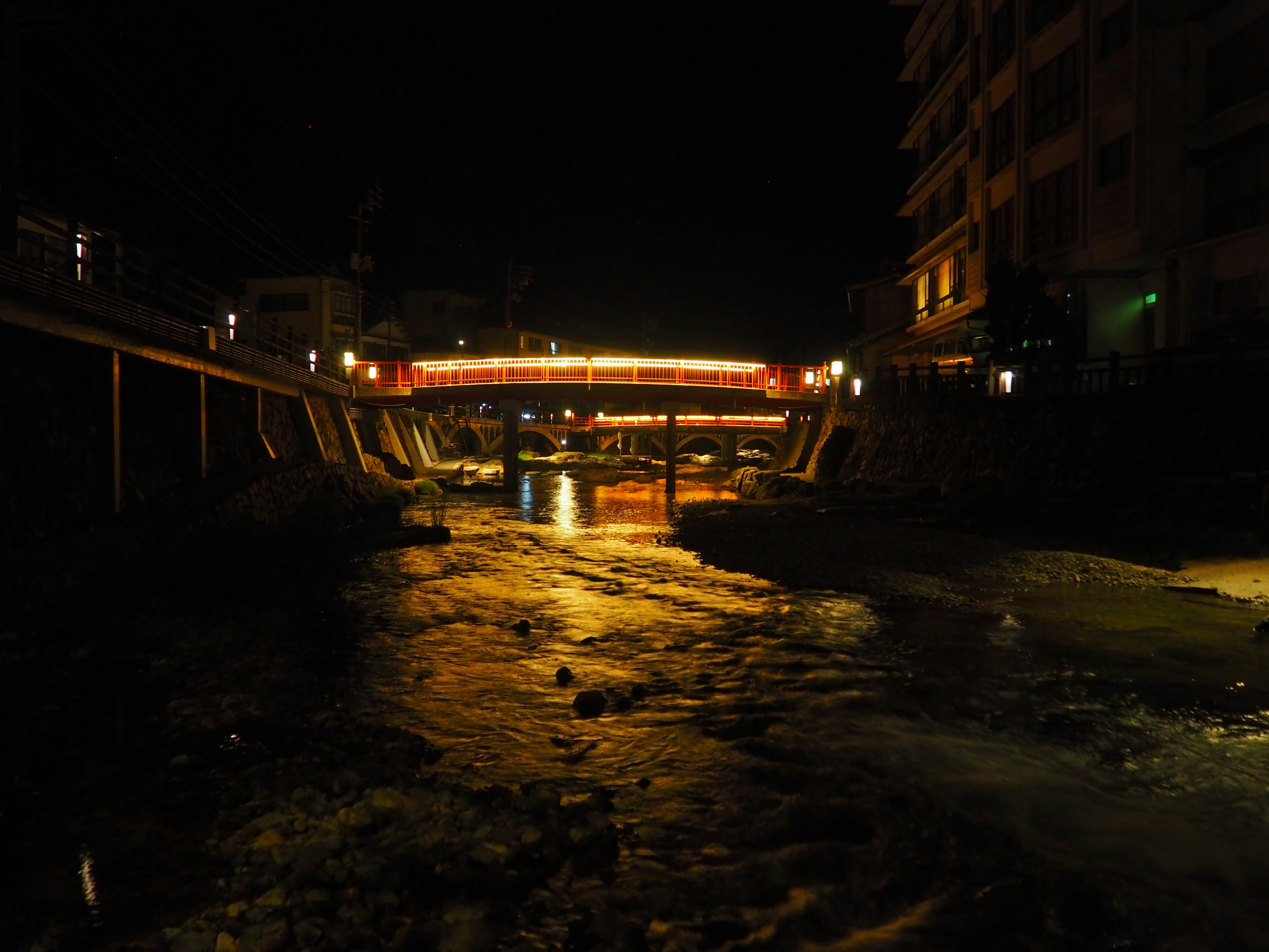 Vista nocturna de un río con un puente iluminado