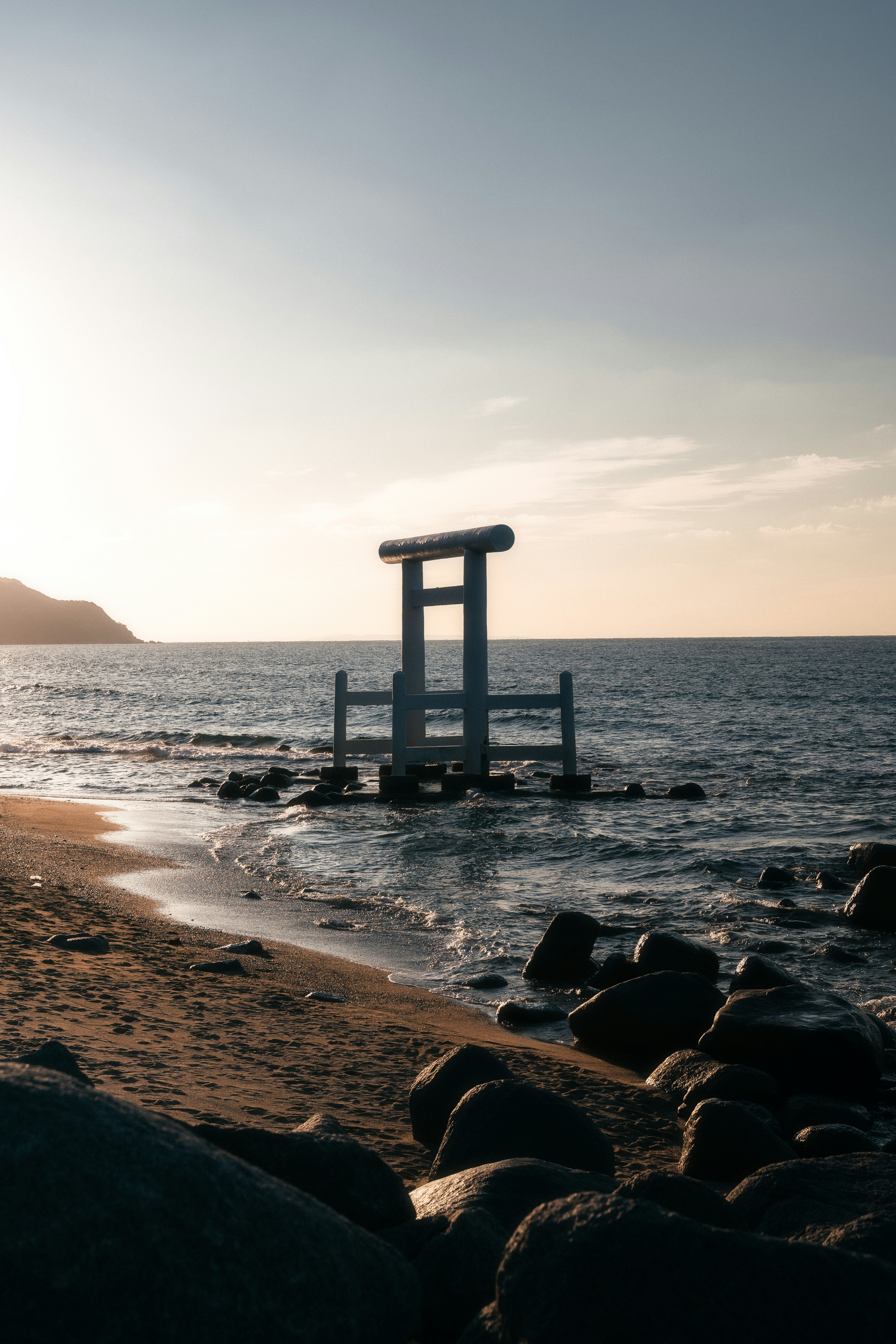 Gerbang torii putih dekat laut dengan batu