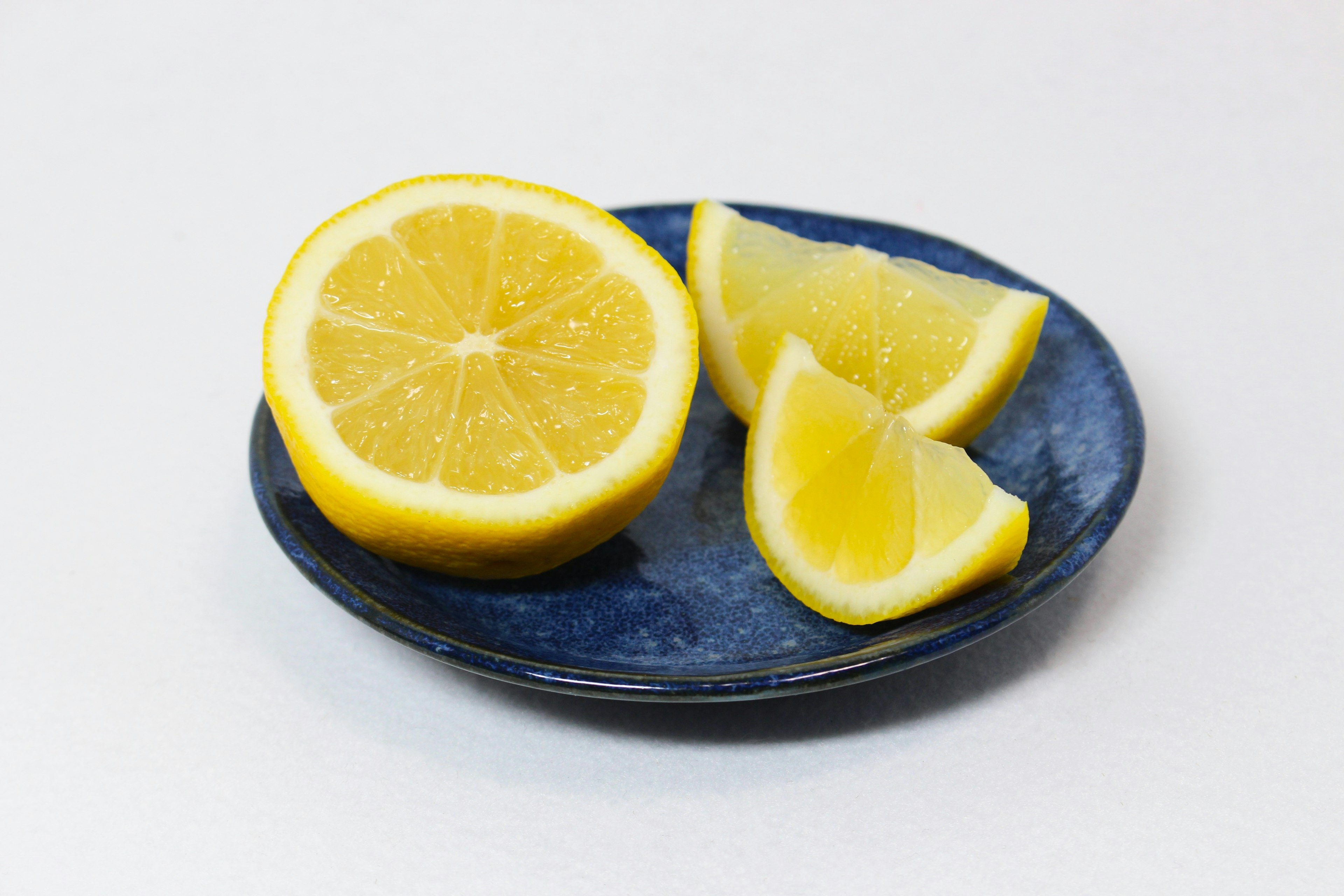 Lemon slices and half a lemon on a blue plate