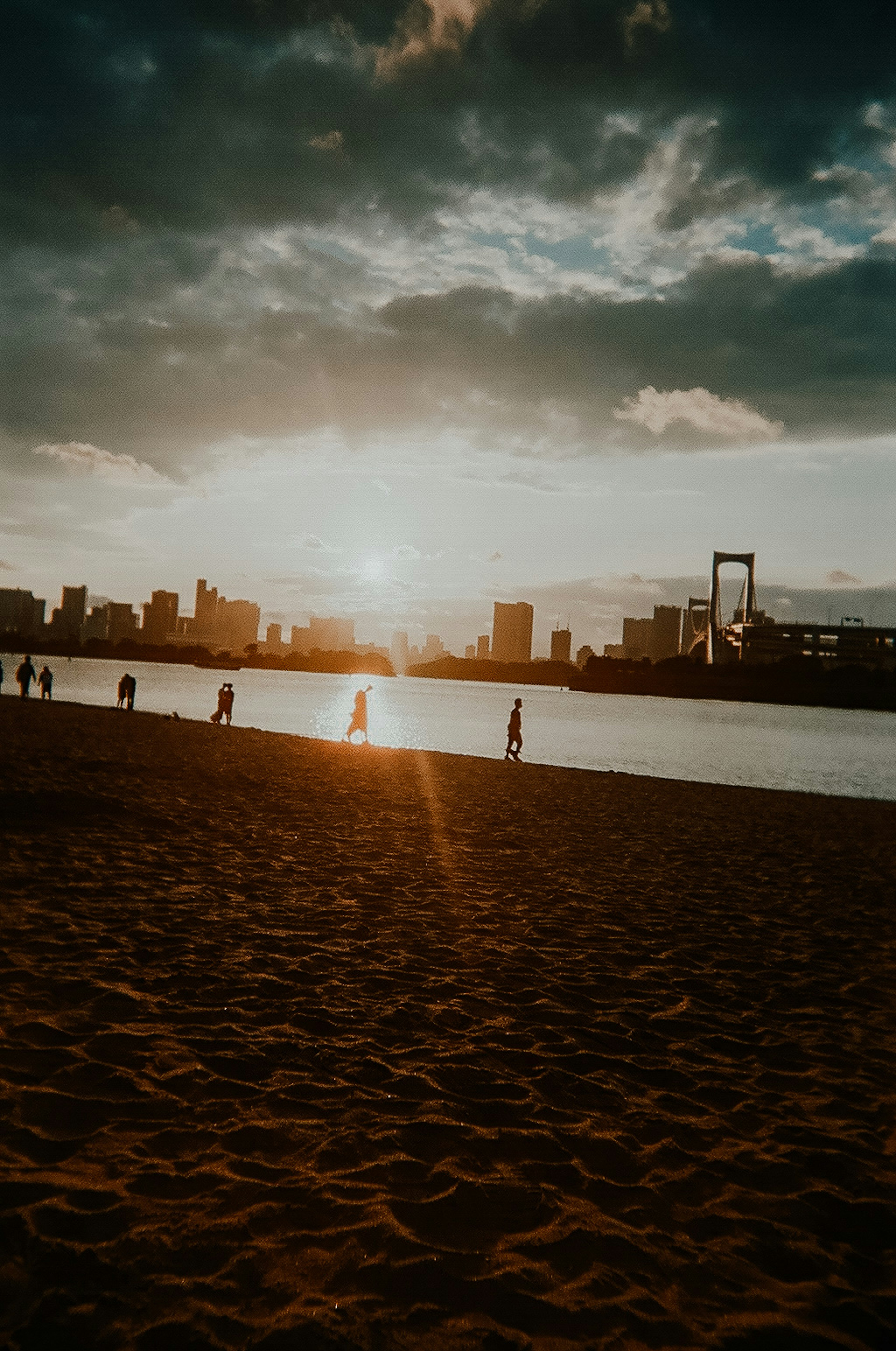 Silhouette of a city skyline at sunset with a sandy beach